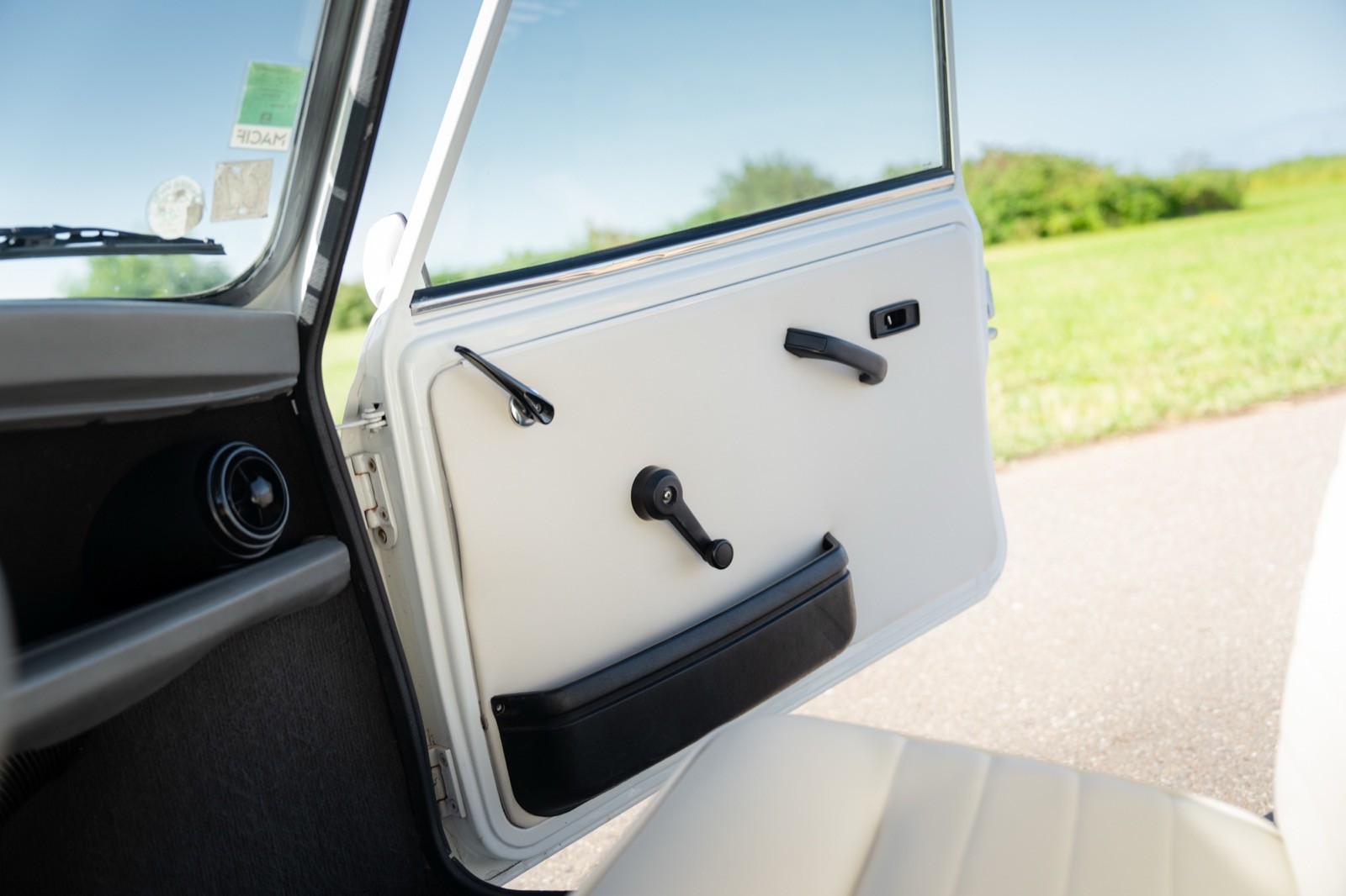 Close-up of a car door interior, showcasing the door handle and controls, with a scenic outdoor view visible.