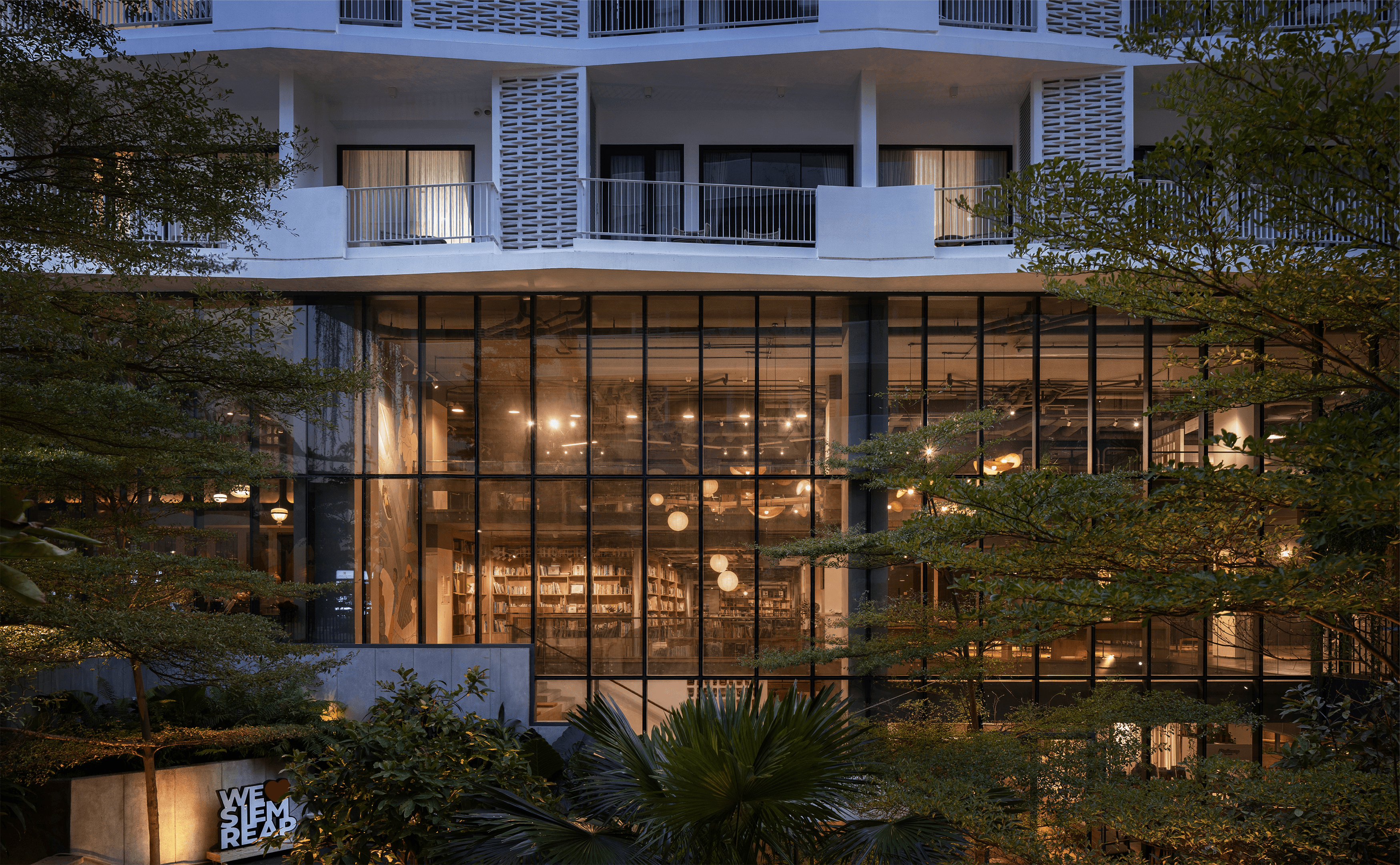 Exterior of Commune Work; coworking project at dusk, showing an activated ground-floor public interface, mature landscaping and a building designed to support its occupiers and commercial purpose over time