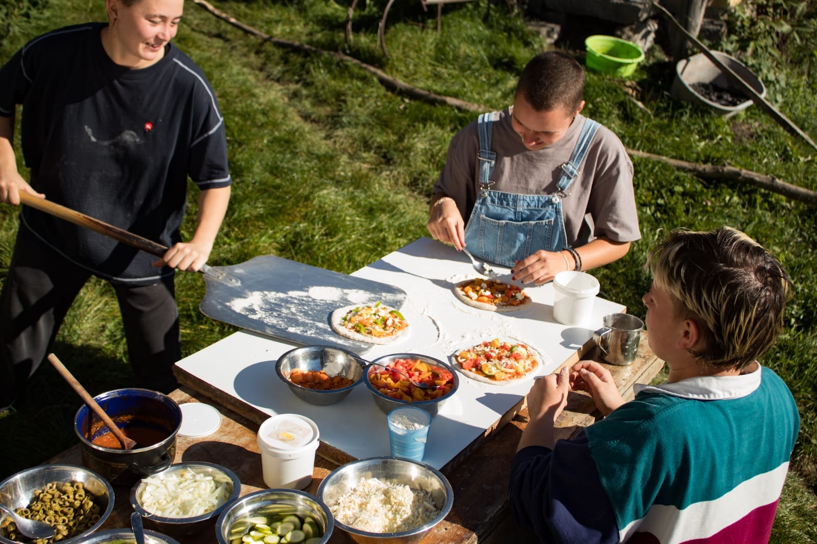 A smiling young man with crossed arms, wearing a plaid shirt and white t-shirt, poses against a dark background.