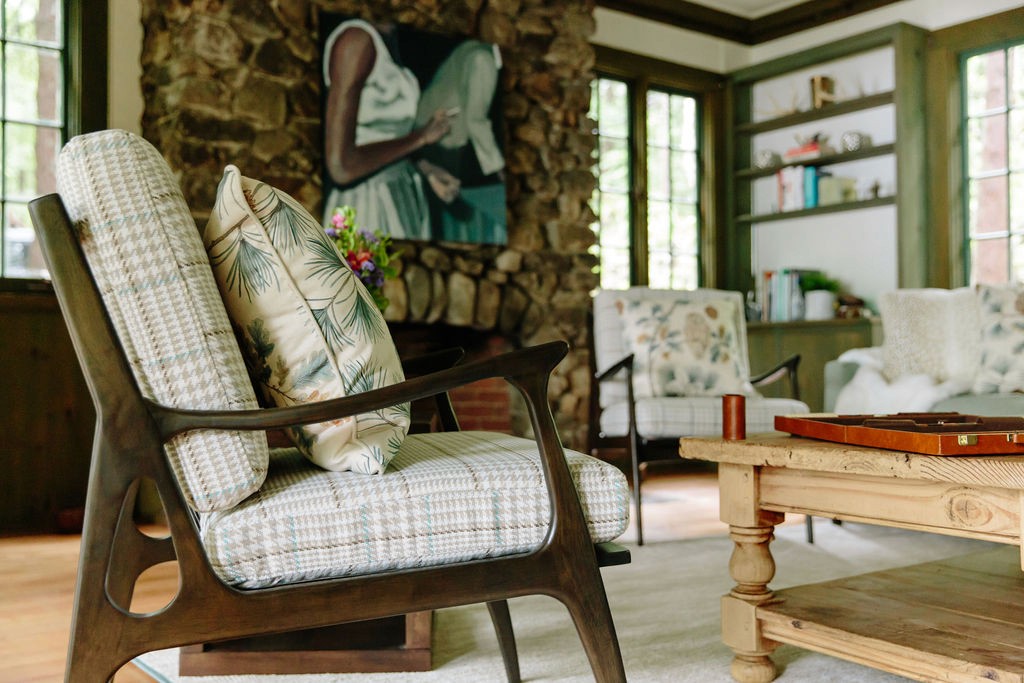 Stone fireplace living room styled with mid-century chair and patterned pillows, photographed by Robyn Ivy.