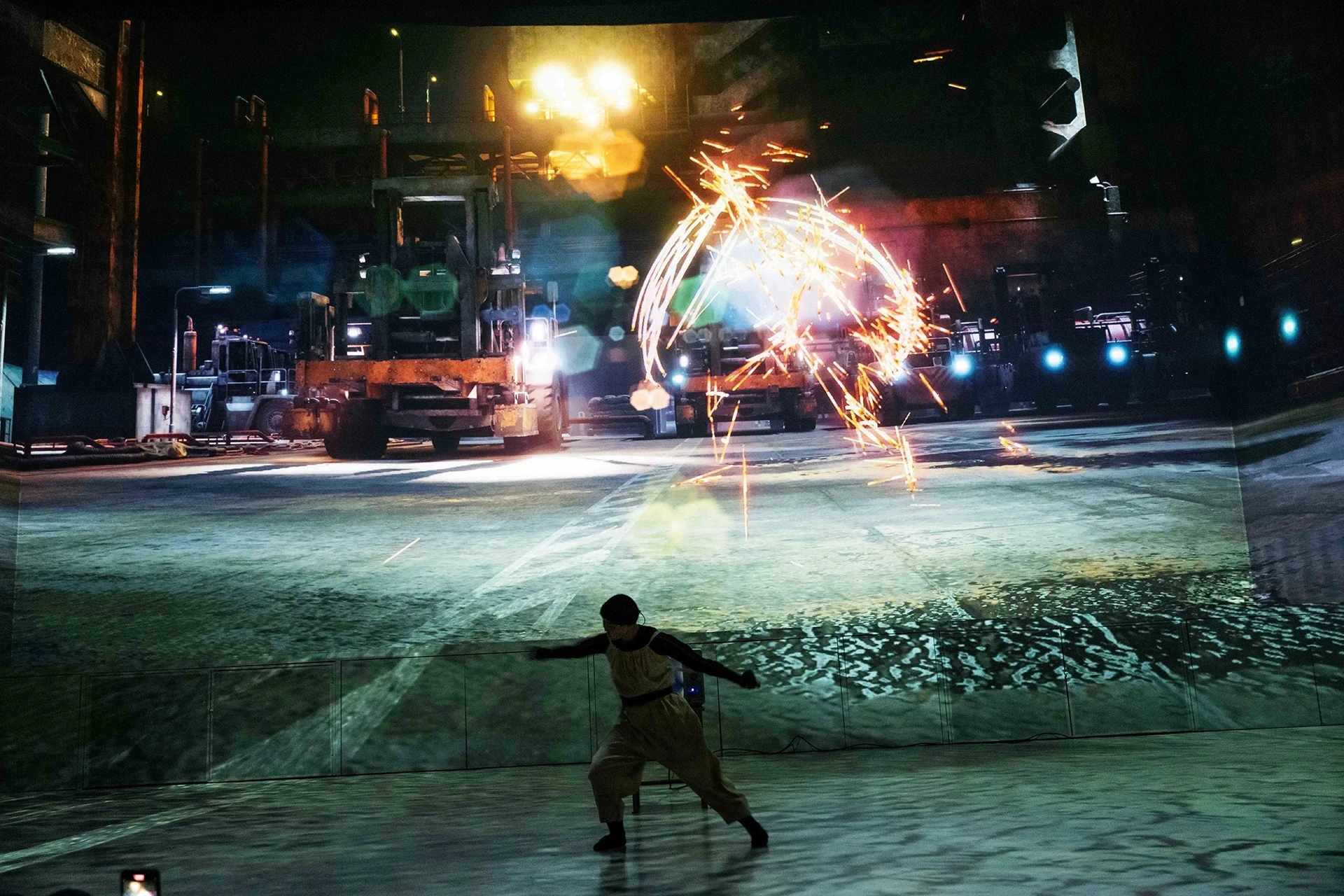 Dancer in foreground with projection of industrial scene and sparks
