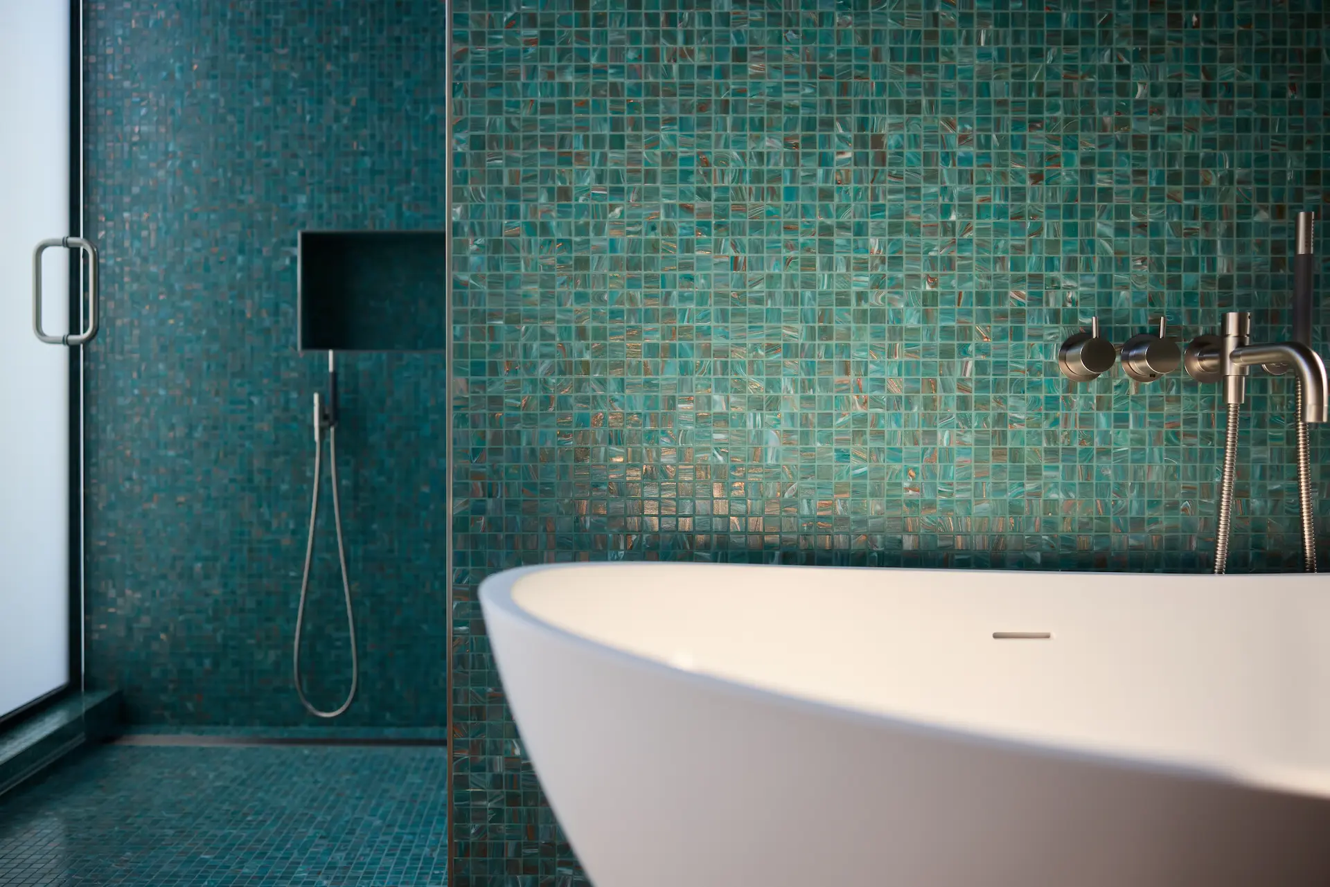 Close-up view of the master bath's tub and shower area, showcasing luxurious finishes and modern fixtures in this Eichler remodel. Photo by Todd Huge.