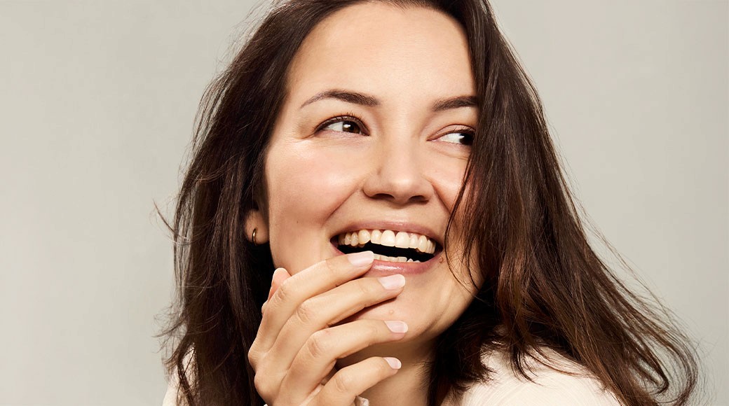 Woman with brown hair and mustache smiling