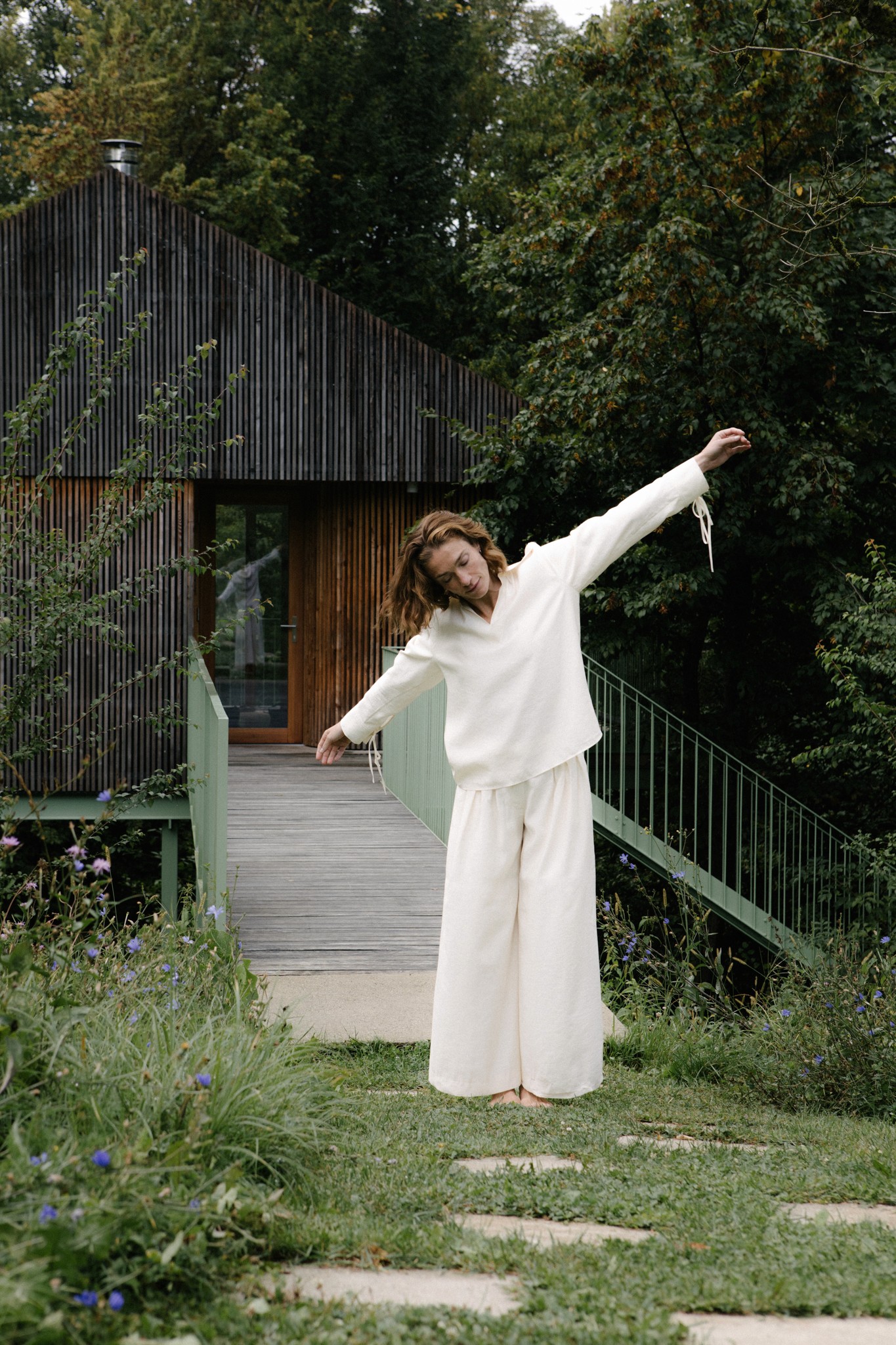 Frau im Garten vor modernem Haus – natürlicher Lebensstil mit Oresa