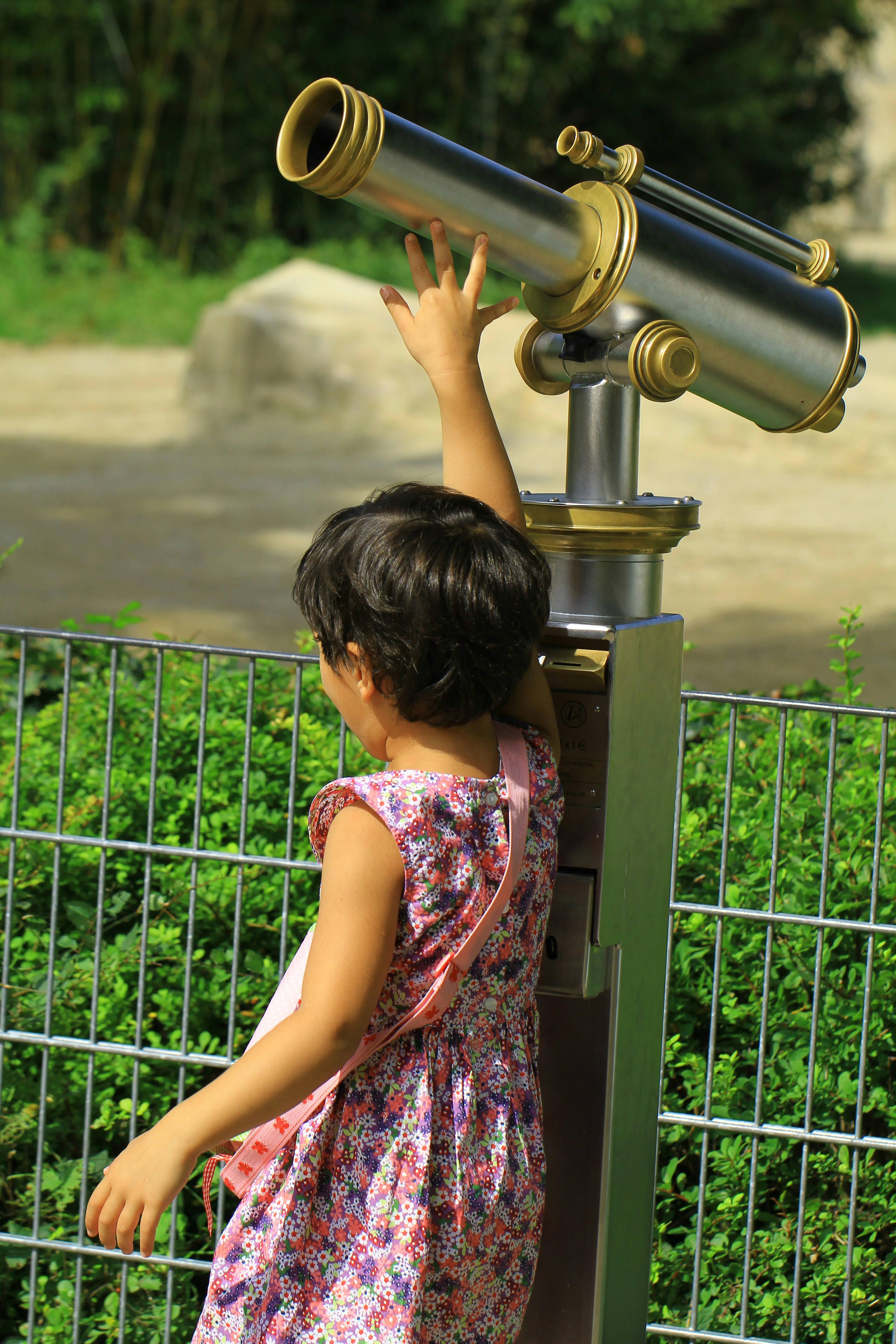 A young girl looks through a large telescope.