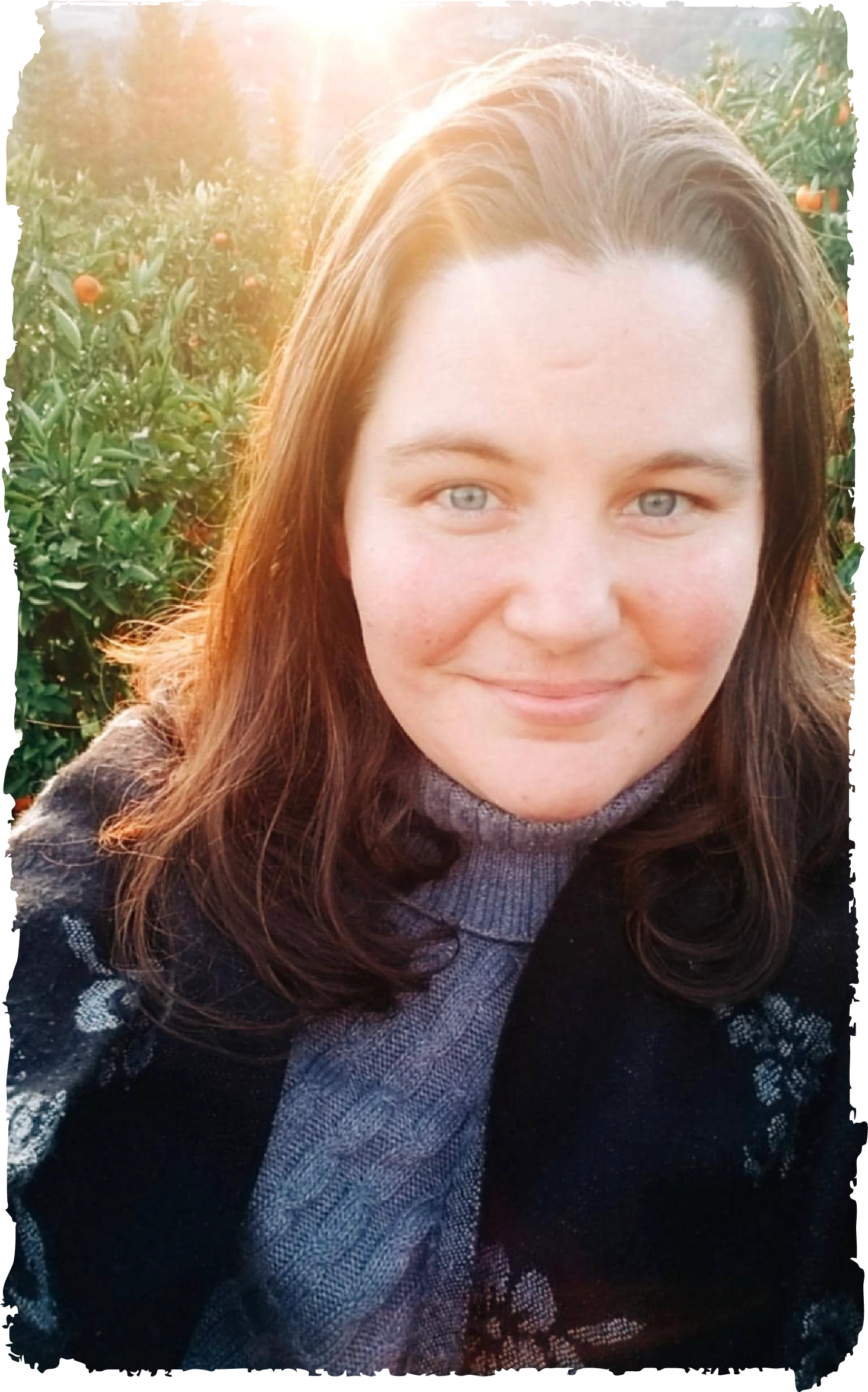 `Jen Rego, brand identity designer, smiling in an orchard with warm backlight`