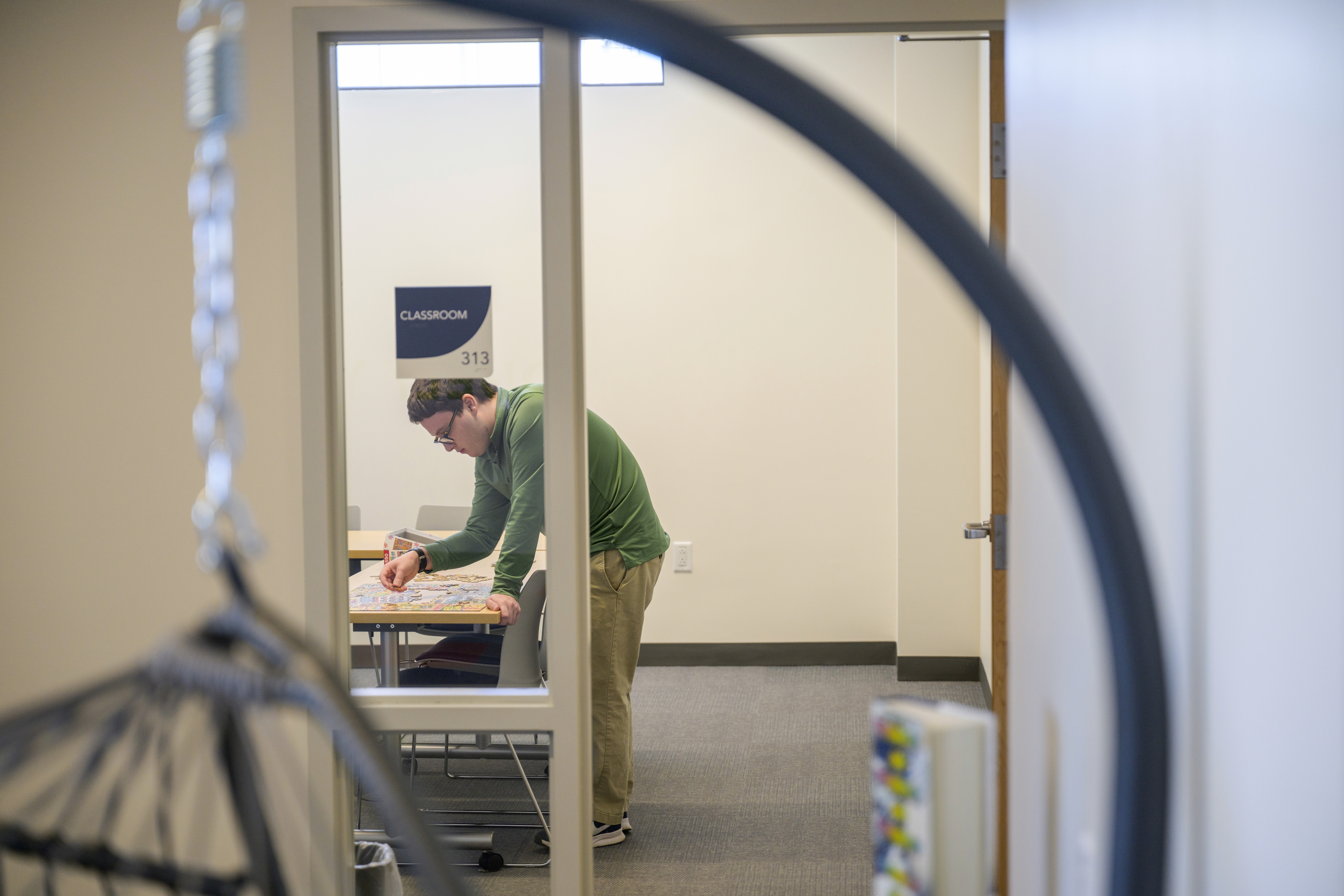 A desk, with a computer and books, and a person sitting writing in a journal