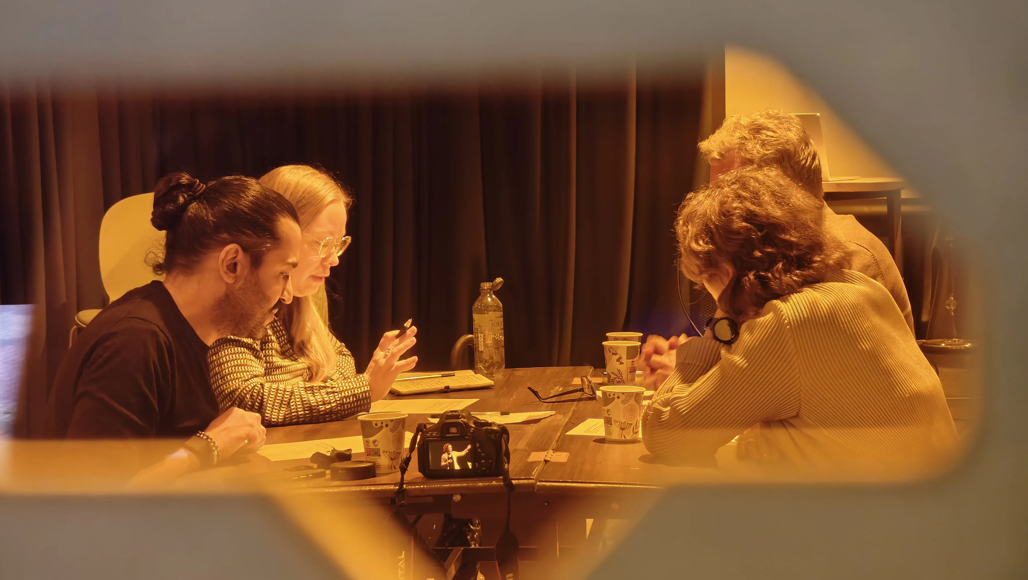 A group of people talking and sitting down around a table