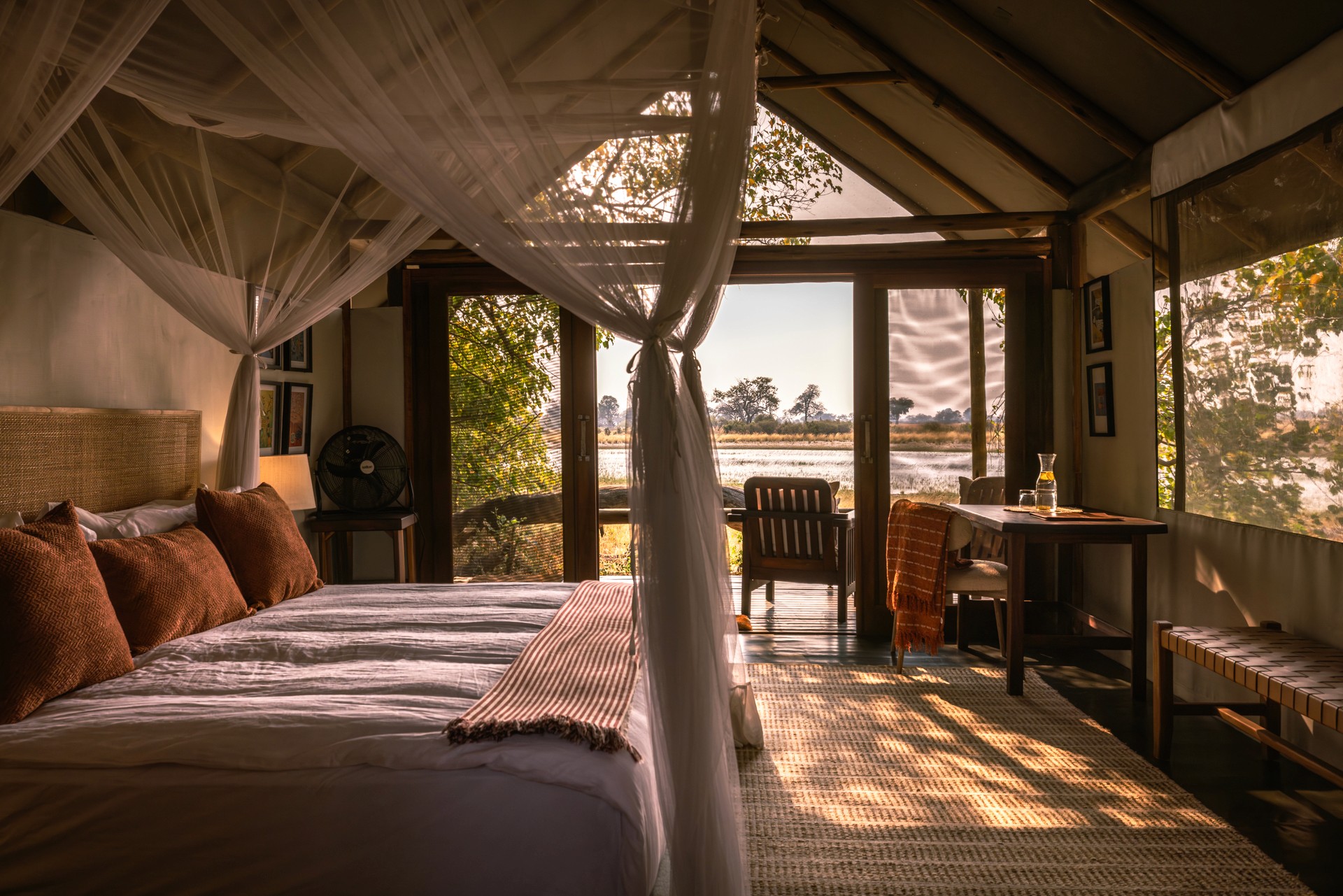 Kujwana Delta Ride, Okavango Delta, Botswana. Lyxigt och rymligt boende på Kujwana Camp. Vackert bäddad dubbelsäng med myggnät runtomsig, mjuk matta på golvet, lampor som ger ett mysigt sken och öppna dörrar från rummet som har utsikt över Okavango Delta.