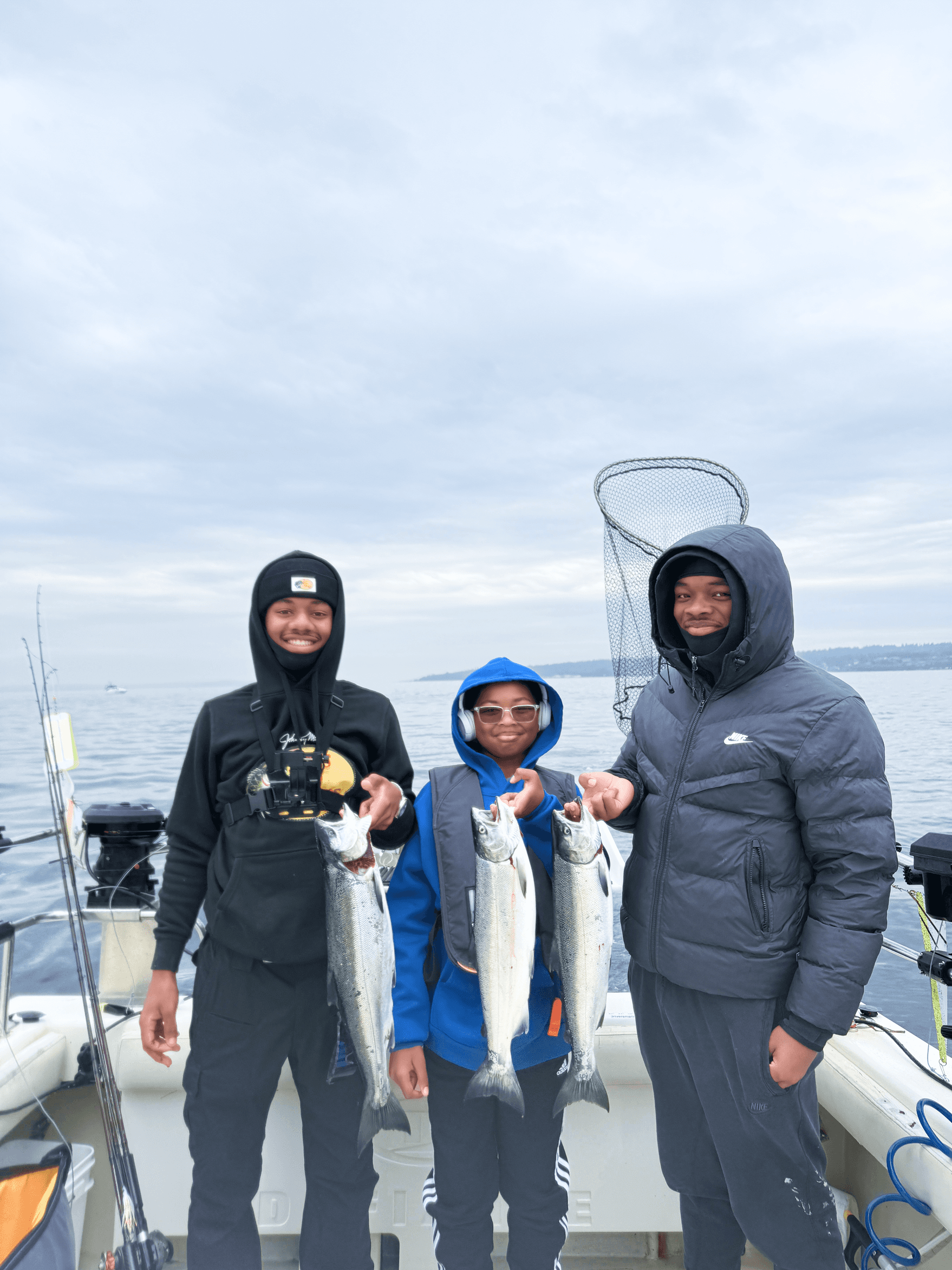 Teens and guide holding coho salmon on Seattle charter boat.