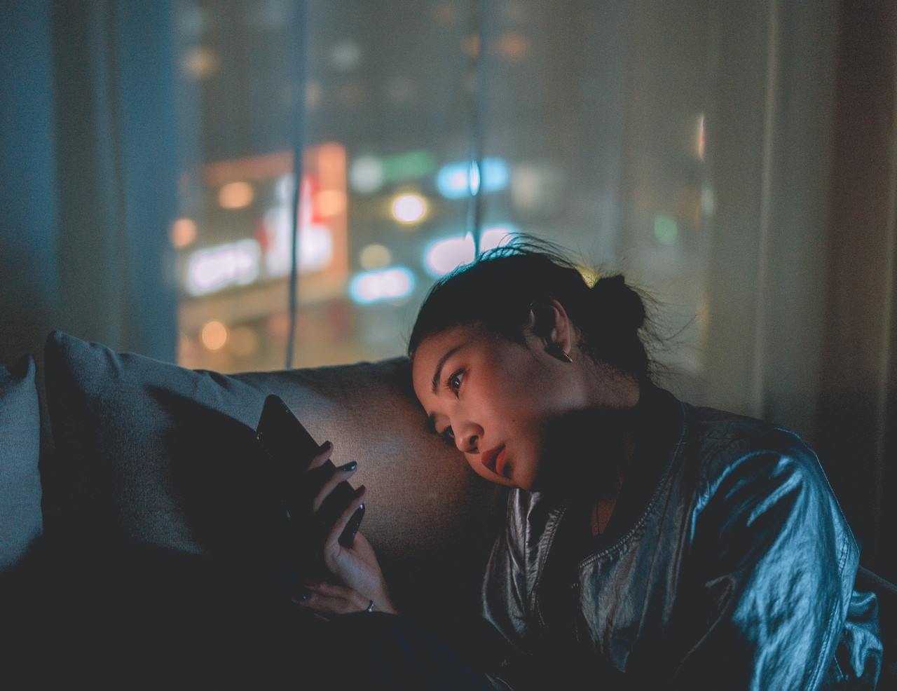 Woman using her phone at night, representing late-night scrolling, information overload, and the impact of screen time on mental health.