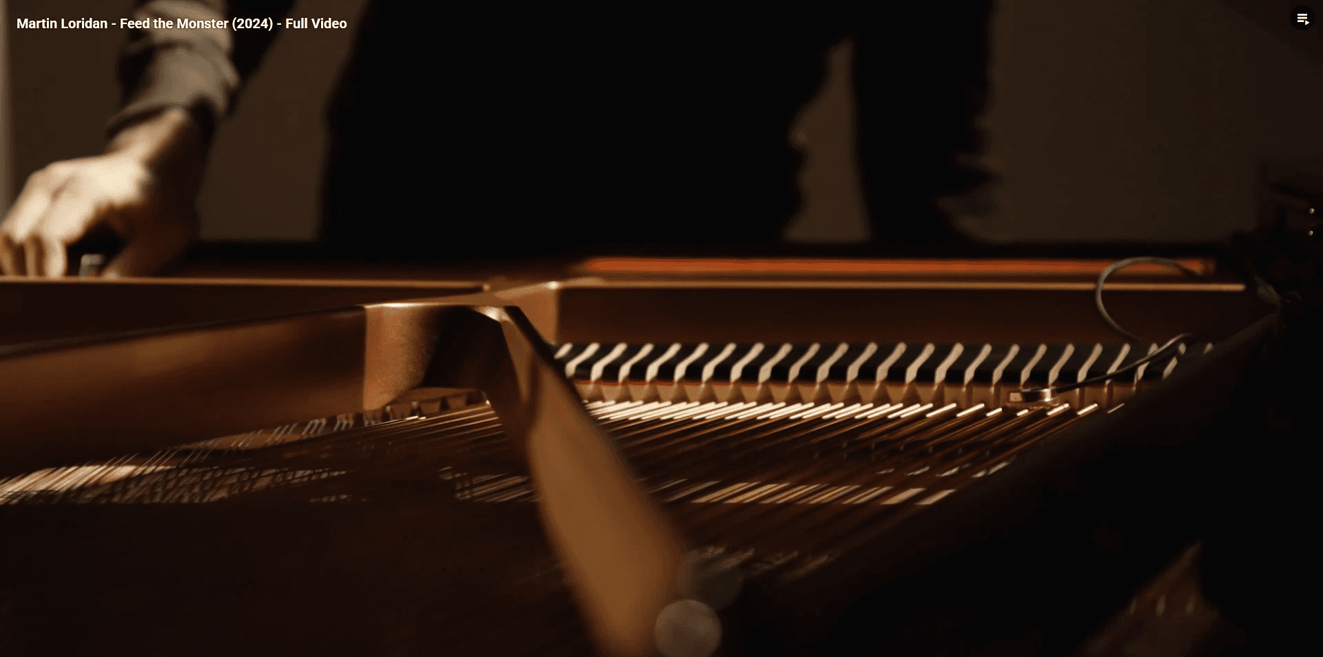Performer working inside an open grand piano on an empty concert-hall stage.