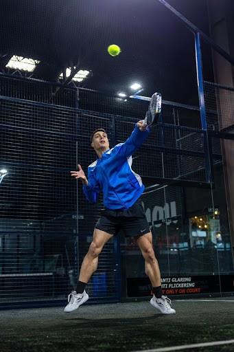 Jugador de pádel realizando un remate durante un entrenamiento en pista indoor en el programa de becas de Padel Pro Camp