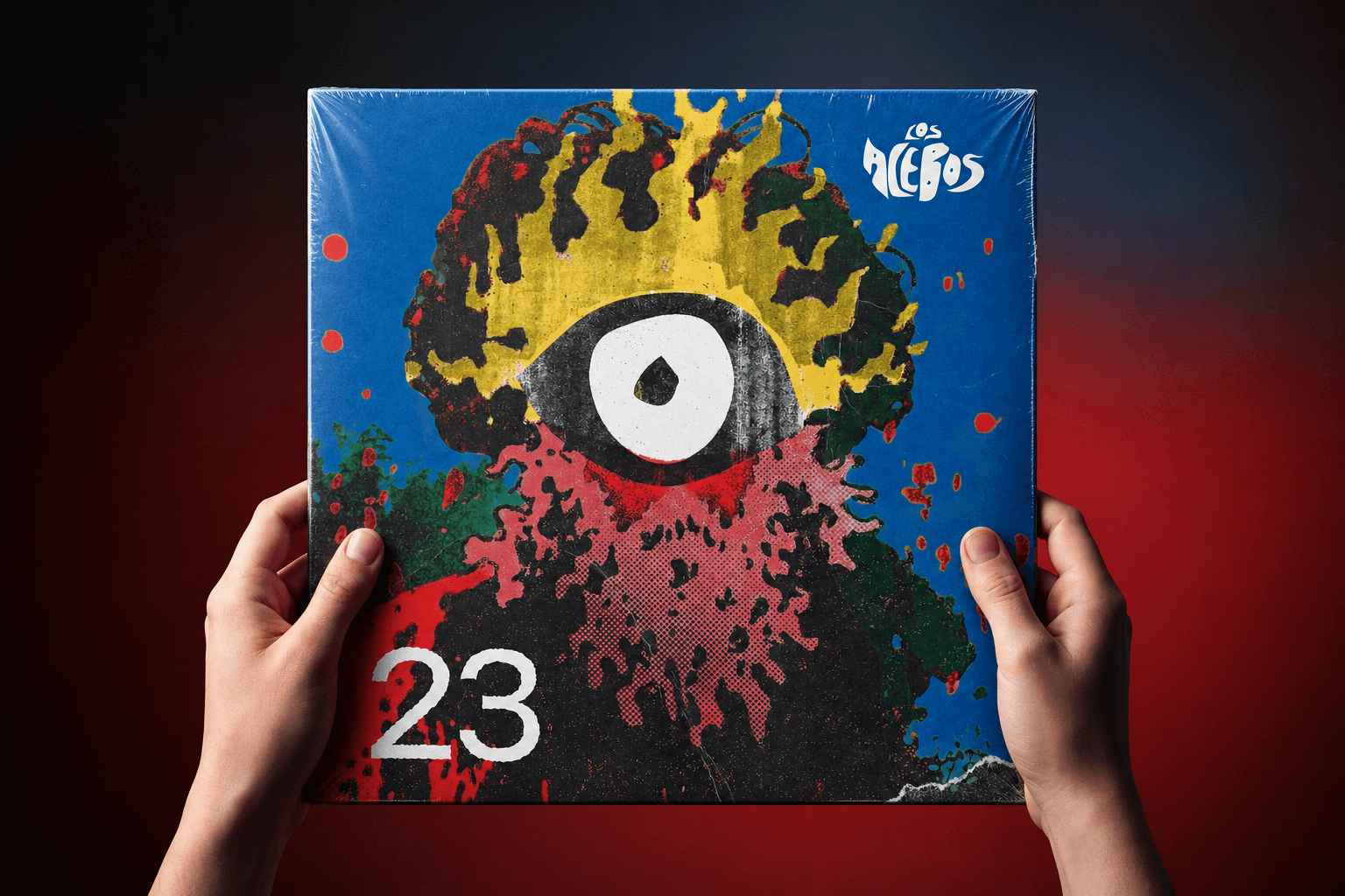 Mockup del álbum 23 de Los Acebos sostenido entre dos manos