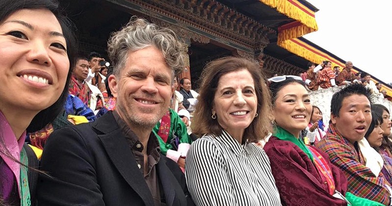 A photo of four people sitting among a crowd near the entrance of an Asian palace.