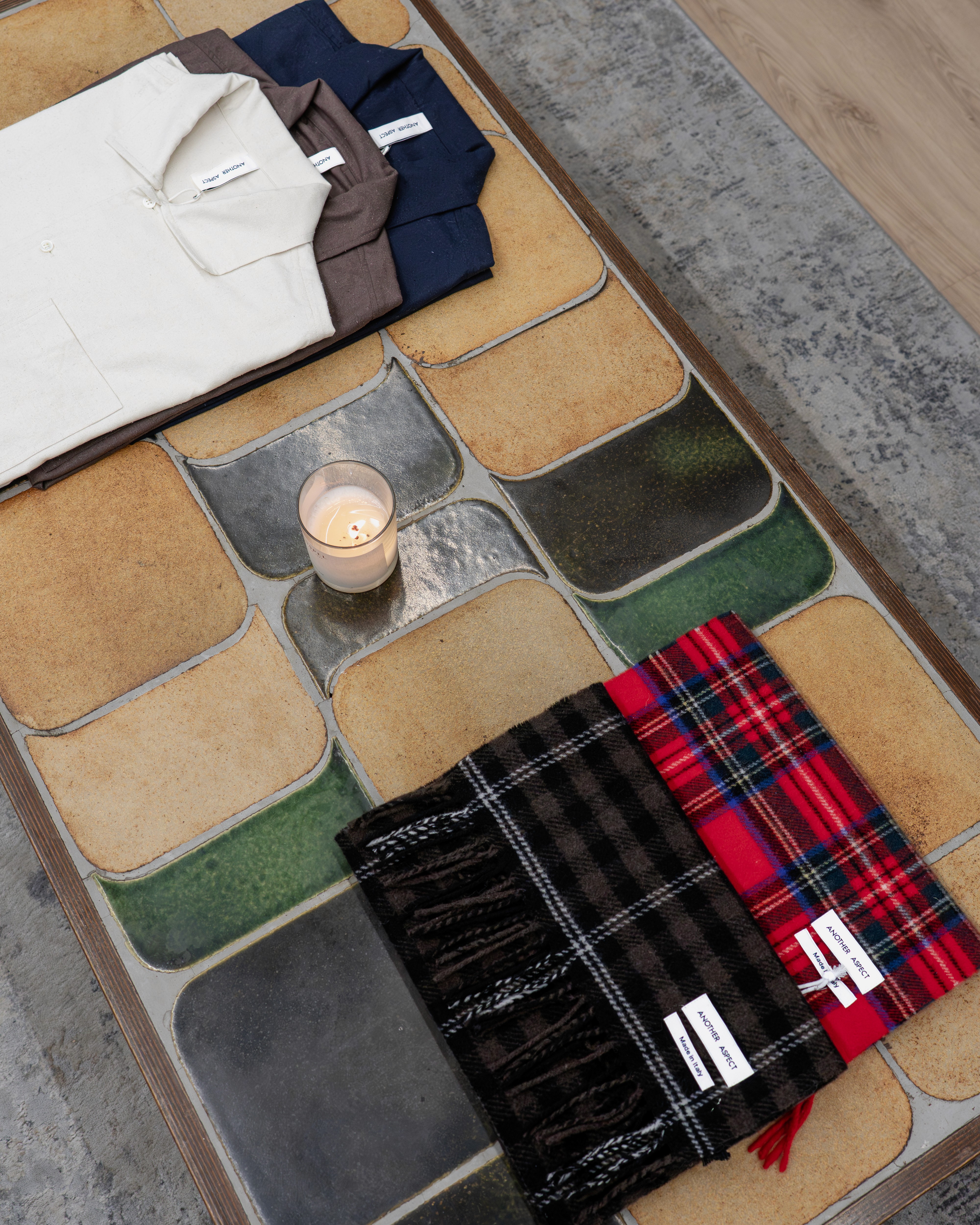 Polos et écharpes Another Aspect posé sur une table du showroom Clothette