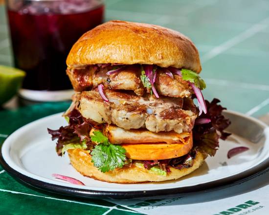 Sandwich Chicharrón du restaurant latino Compadre à Paris, garni de chicharrón de porc croustillant, salsa criolla, patate douce, salade iceberg et mayonnaise épicée. Une spécialité street food sud-américaine servie près de Notre-Dame