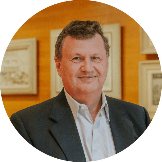 A man in a formal suit stands in an art gallery with wooden walls and framed artwork in the background, creating a sophisticated atmosphere.