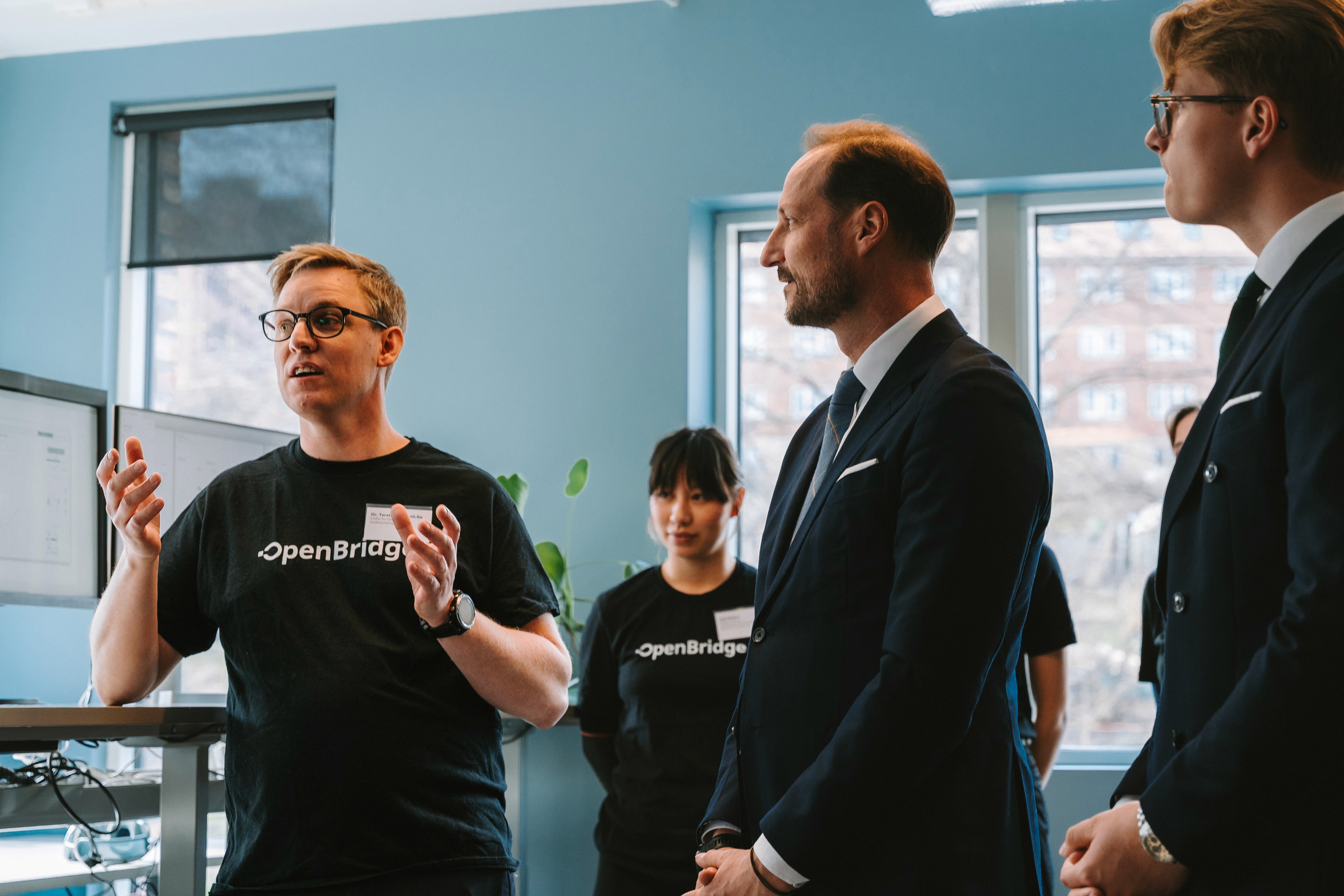 A person wearing a virtual reality headset stands in front of multiple screens, engaged in a digital experience.