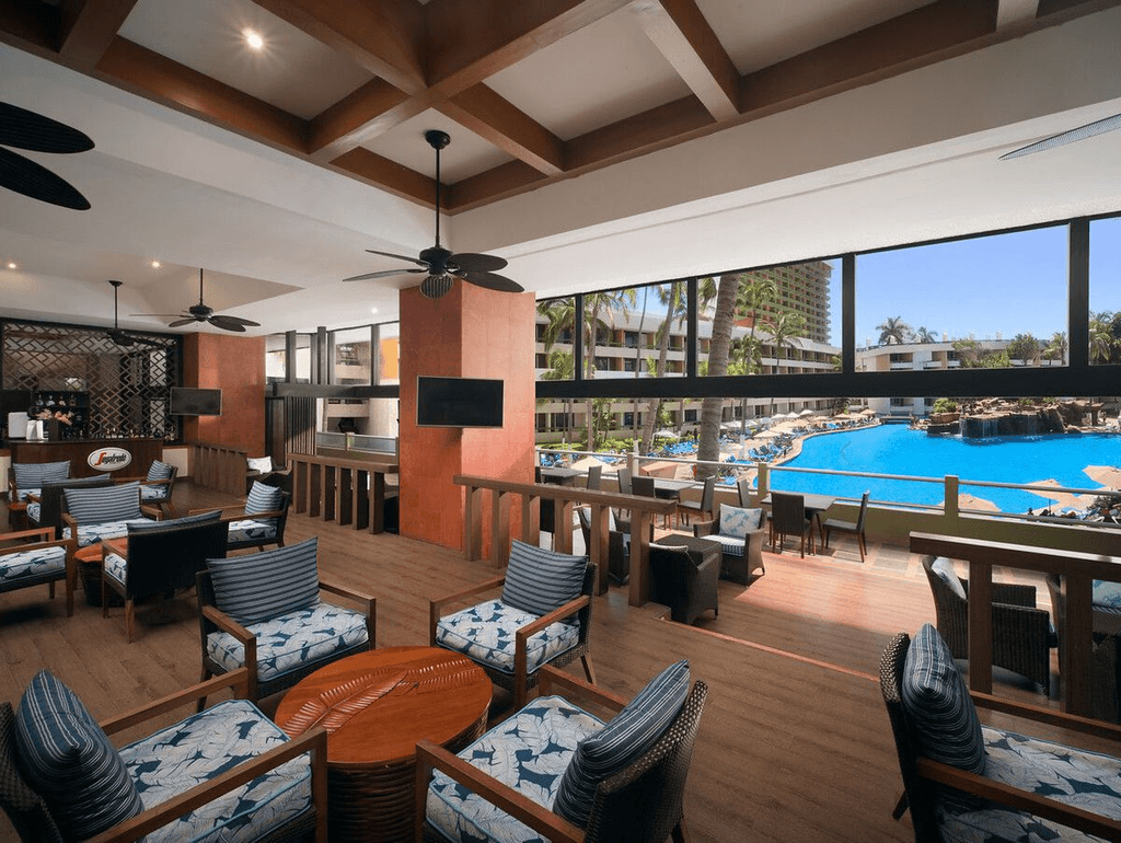 Couple standing on a balcony with binoculars in hand looking out over the ocean