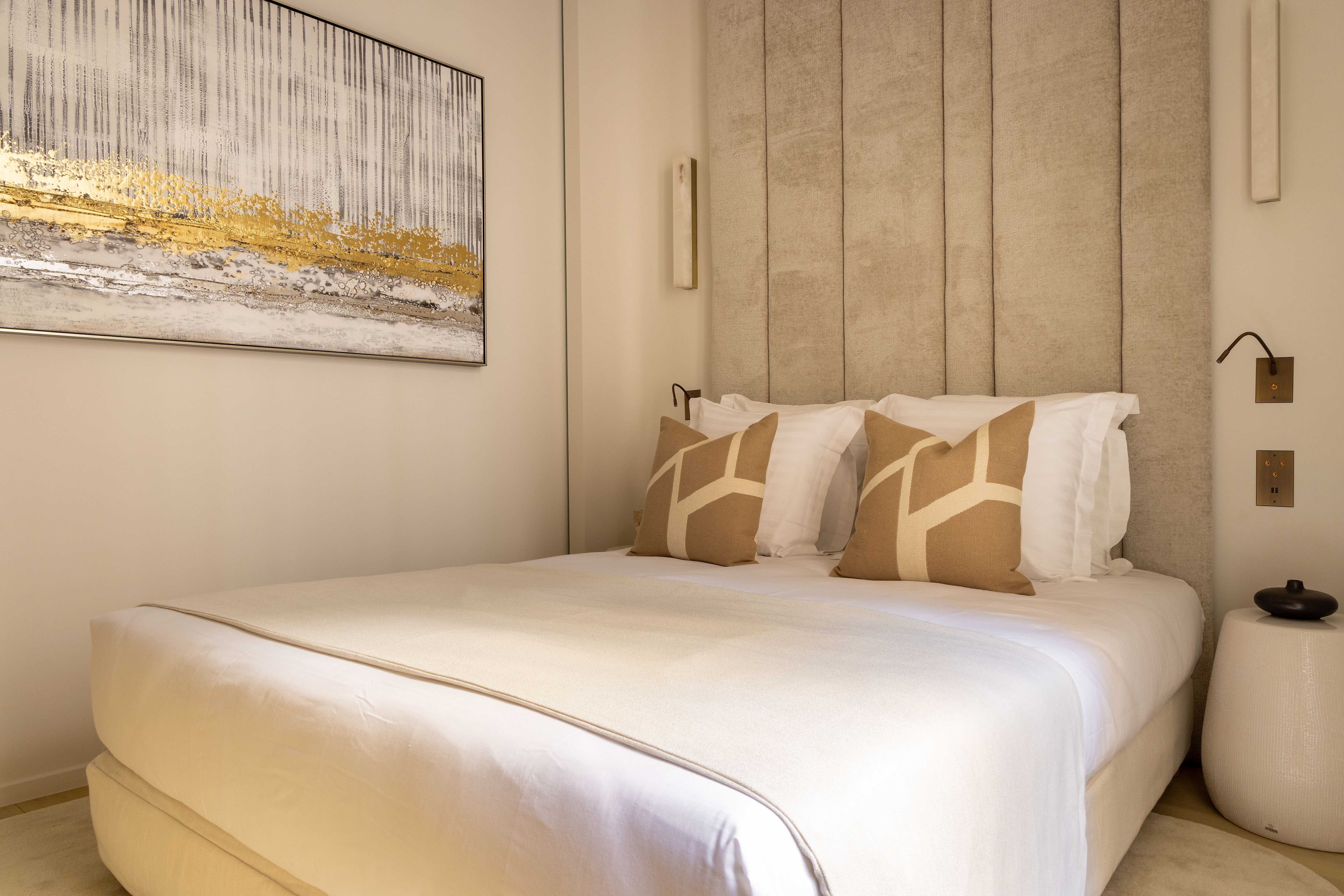 Seconde chambre avec lit double, tableau abstrait doré, coussins graphiques et appliques