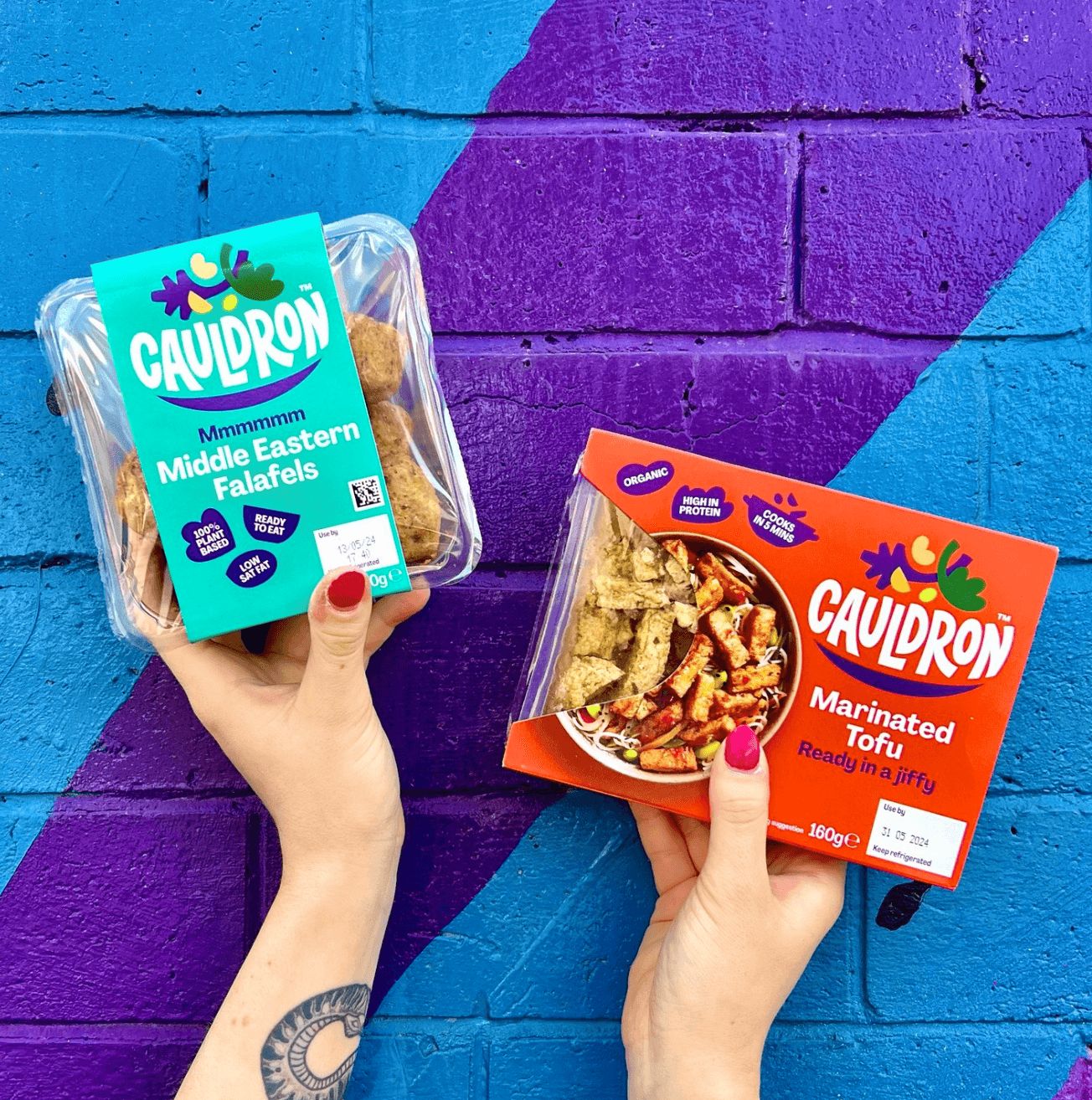 Holding Cauldron products near street art