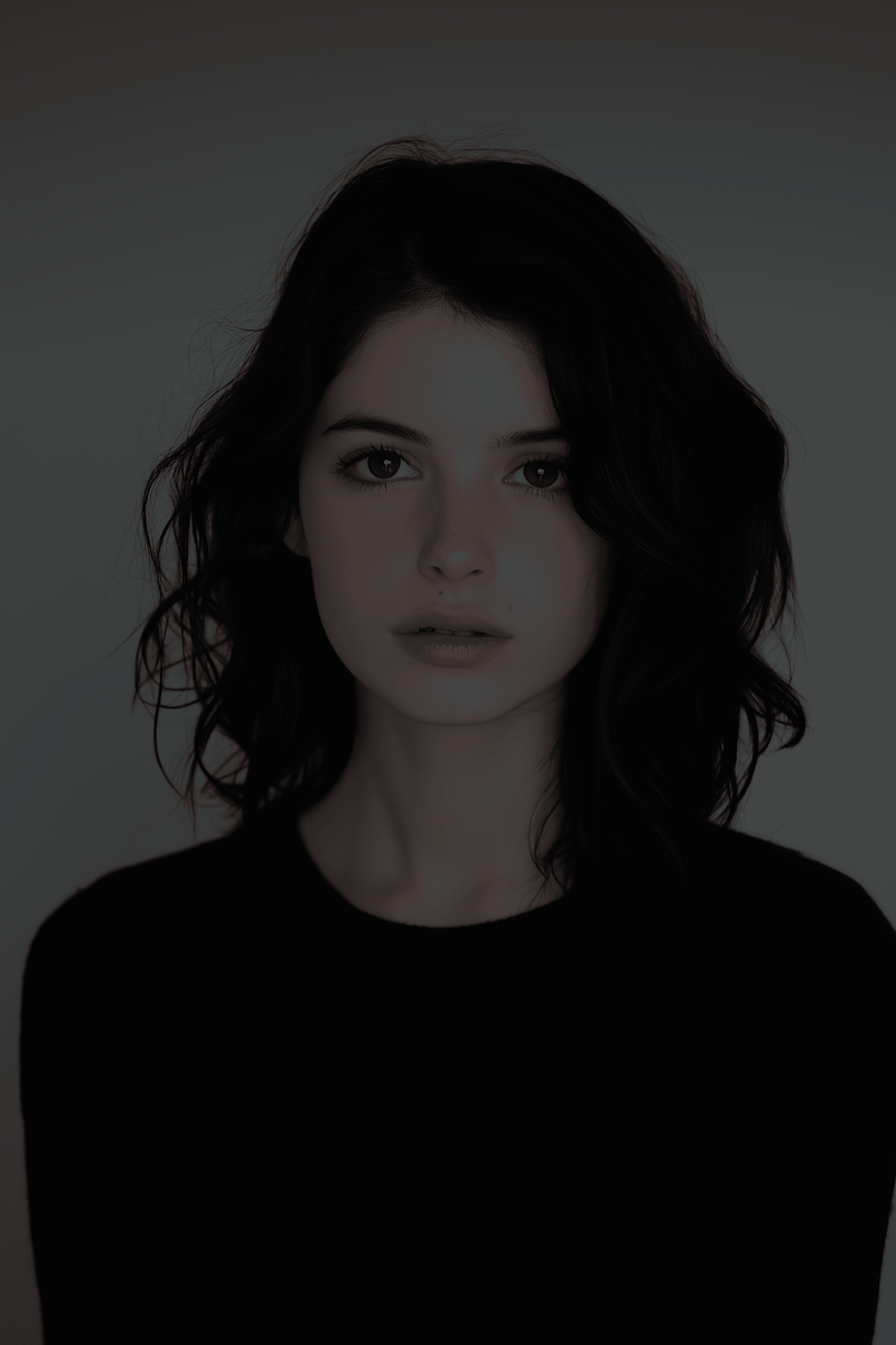Close-up portrait of a young woman with dark hair and eyes, wearing a black shirt against a gray background.