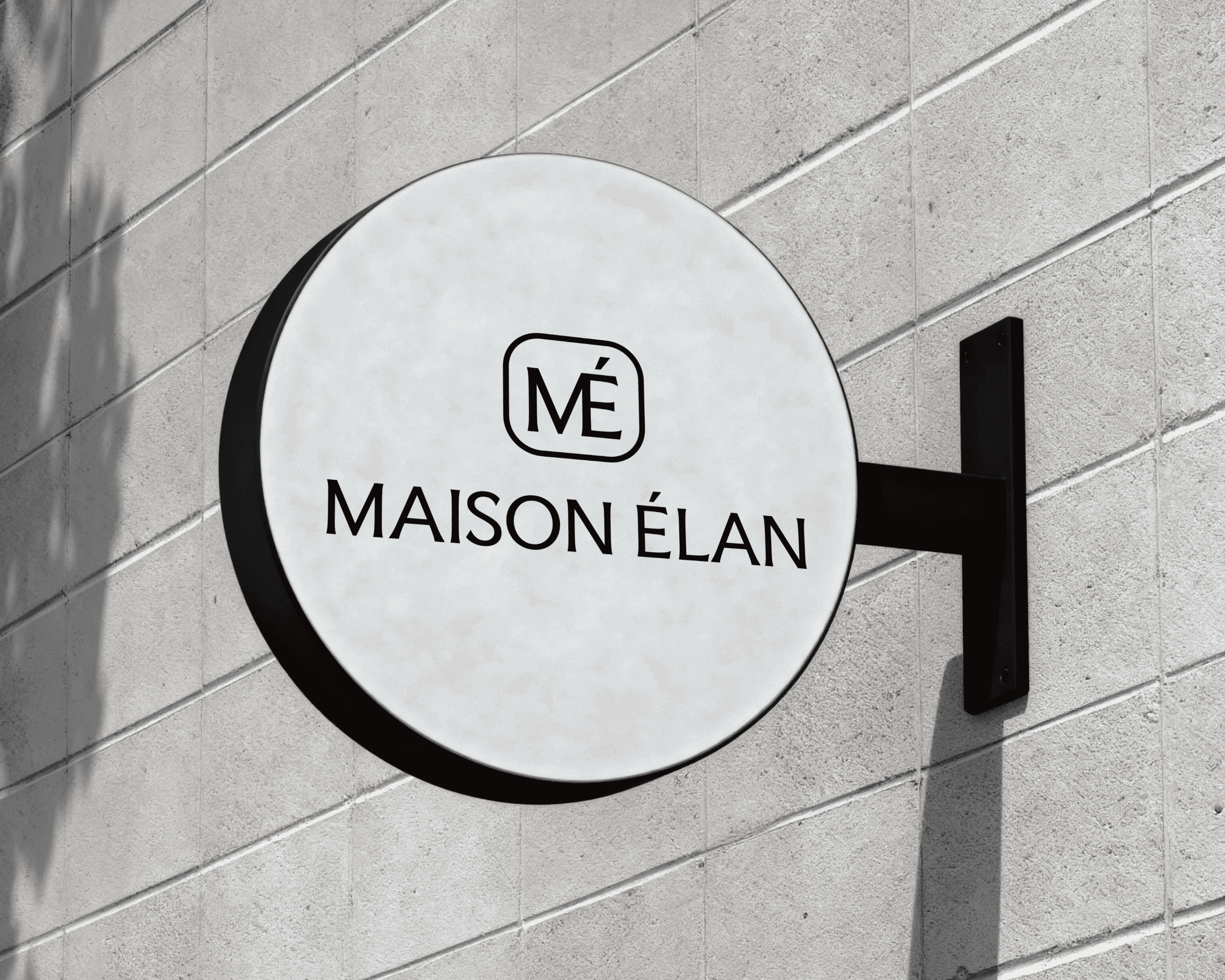 A round outdoor sign with the Maison Élan logo printed on it.
