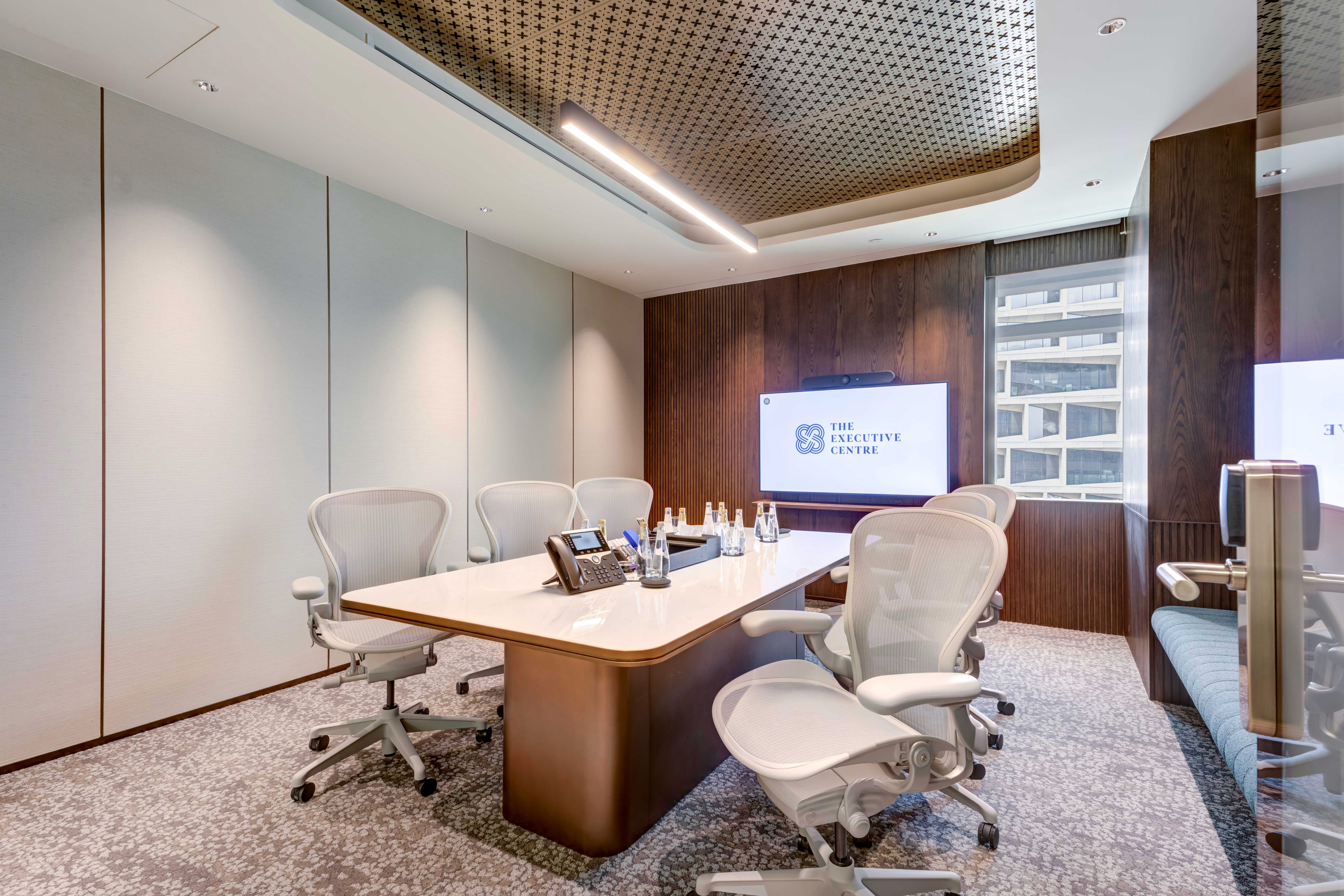 Stylish meeting room with a white table, office chairs, and integrated wall display.
