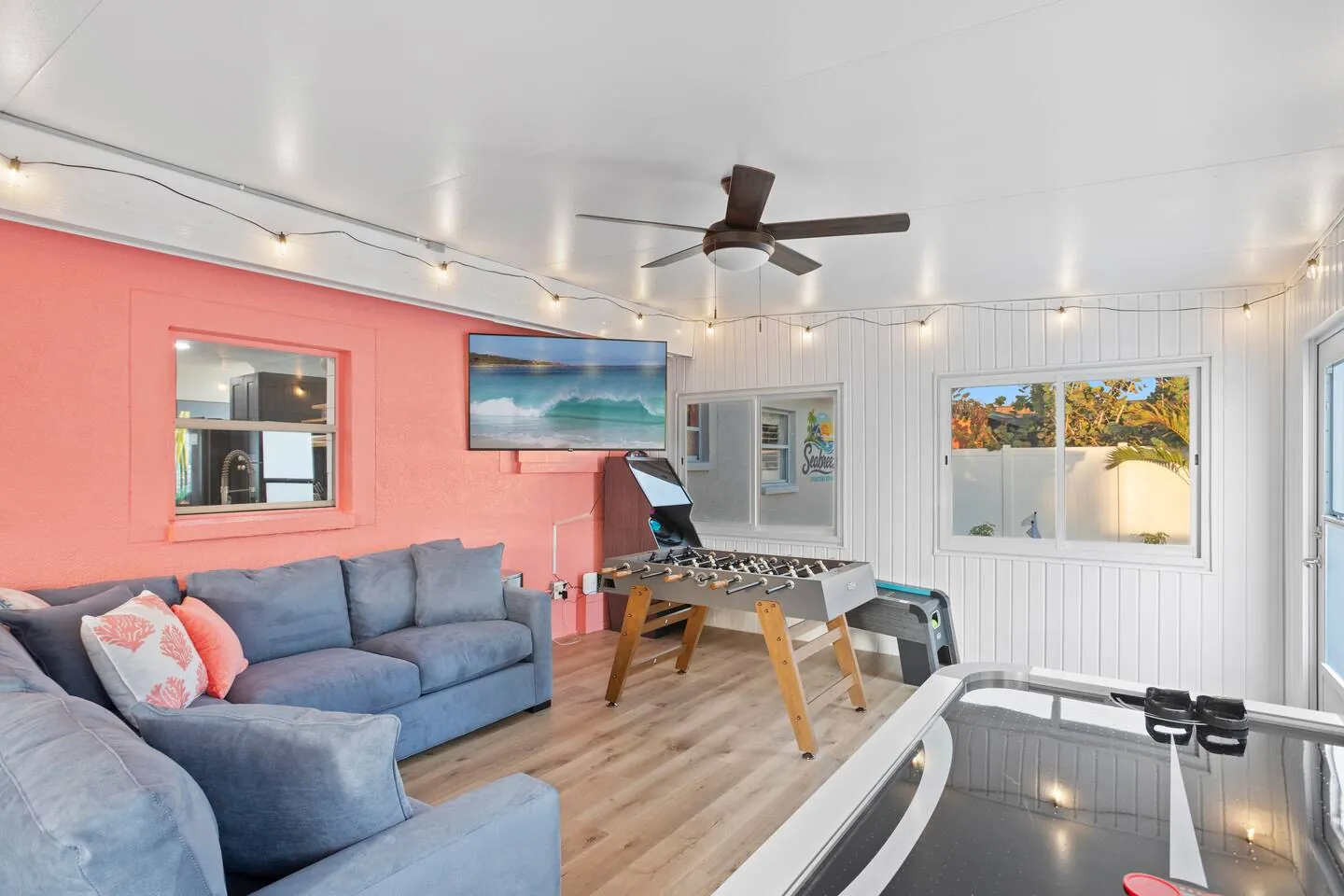 Game room with coral accent wall, sectional, foosball and air hockey at Pickleball Resort, Bradenton, Florida