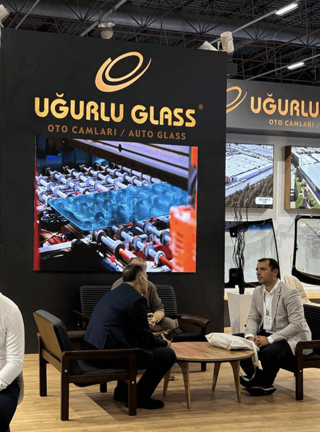 Large illuminated Uğurlu Glass logos and orange lighting details at the Busworld 2026 exhibition stand.