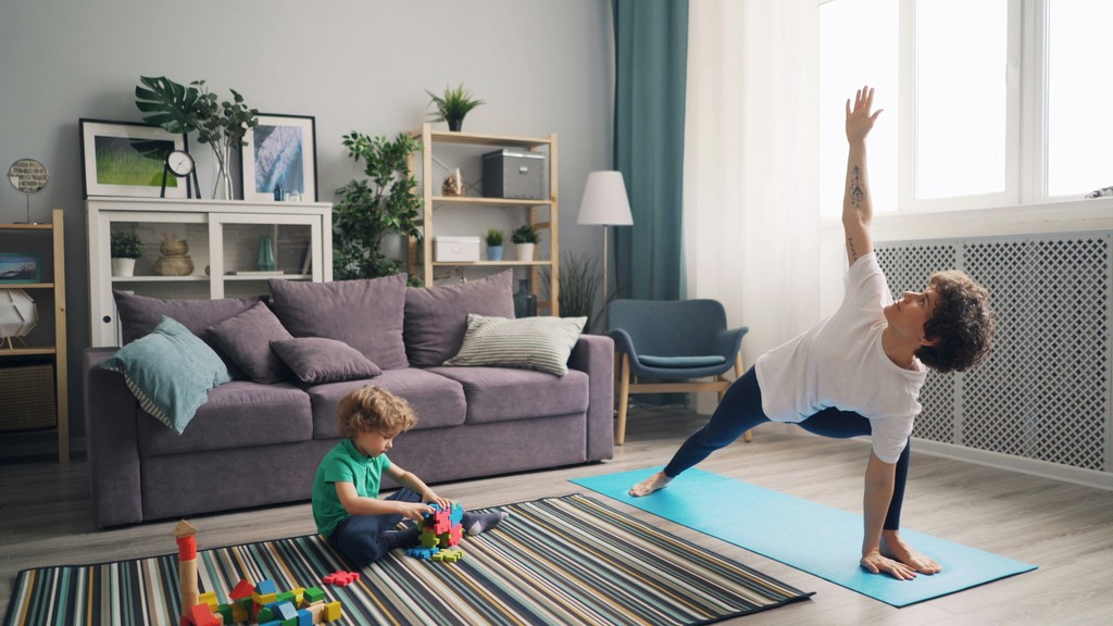 a woman and a child doing yoga in a living room