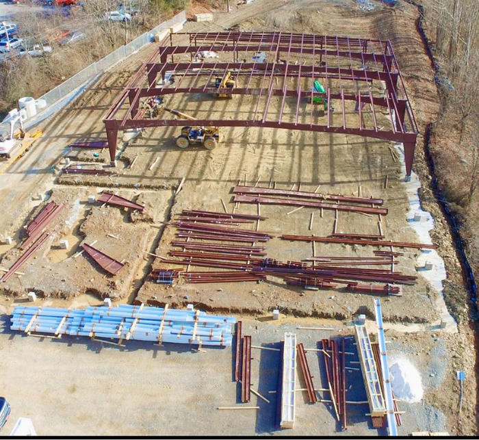 Graded construciton site with metal roof trussed being installed drone shot from above