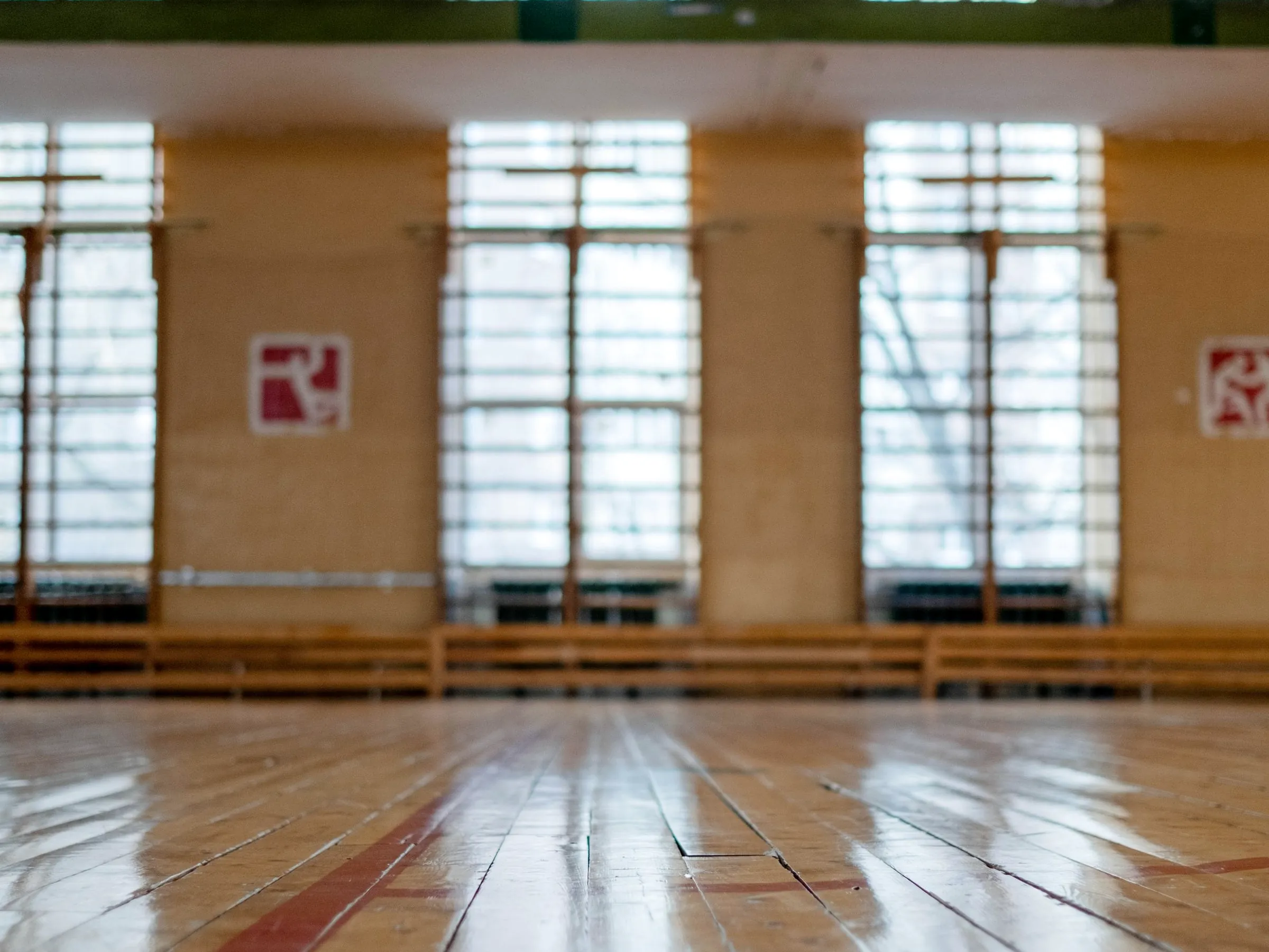 Wooden floor and tall windows of the old community house gym where the Lawrenceville location meets