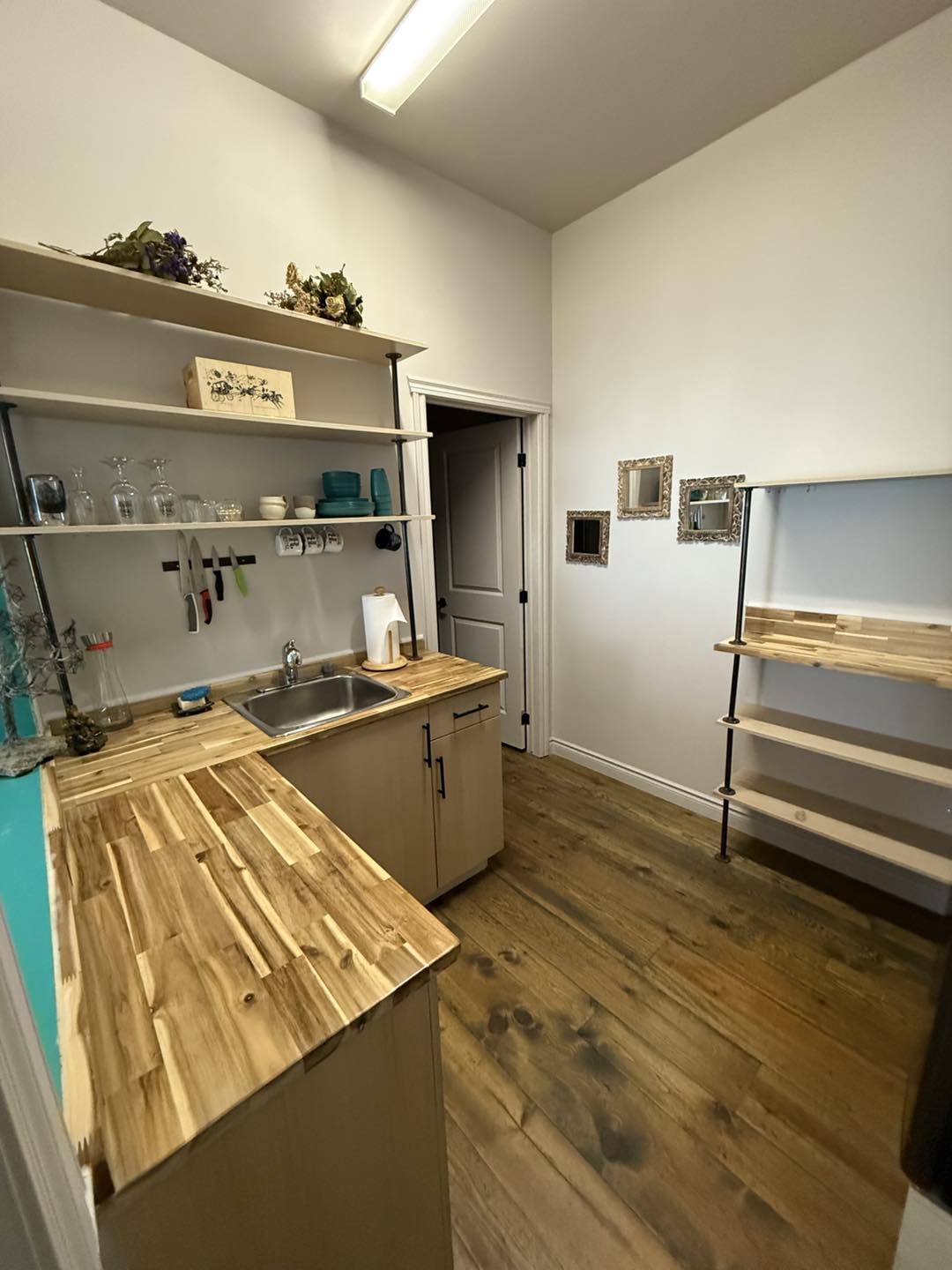 Cuisinette lumineuse de la suite Côté Jardin au gîte R112-Nord, avec comptoirs en bois clair, étagères ouvertes et plancher en bois naturel.