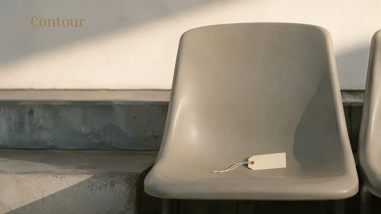 A blank price tag rests on an empty stadium seat beside concrete steps, with the Contour Magazine wordmark at the upper left.