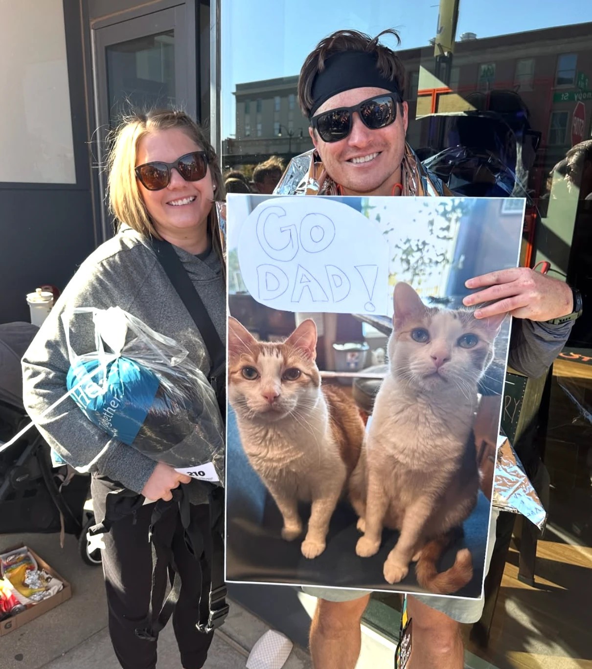 Josh after a race, holding the Go Dad sign his wife made with photos of their two cats