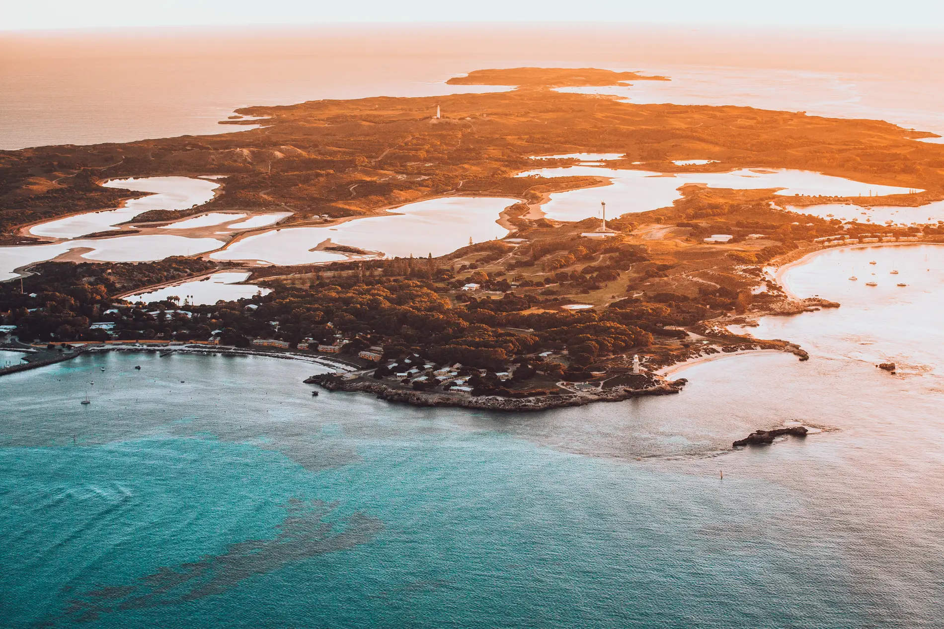Aerial at sunset of an island's bays and salt lakes, boats anchored offshore