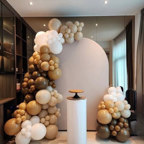 Nude, Brown and white balloon arch in a office. There is a cake stand and a dusty pink arch behind it.