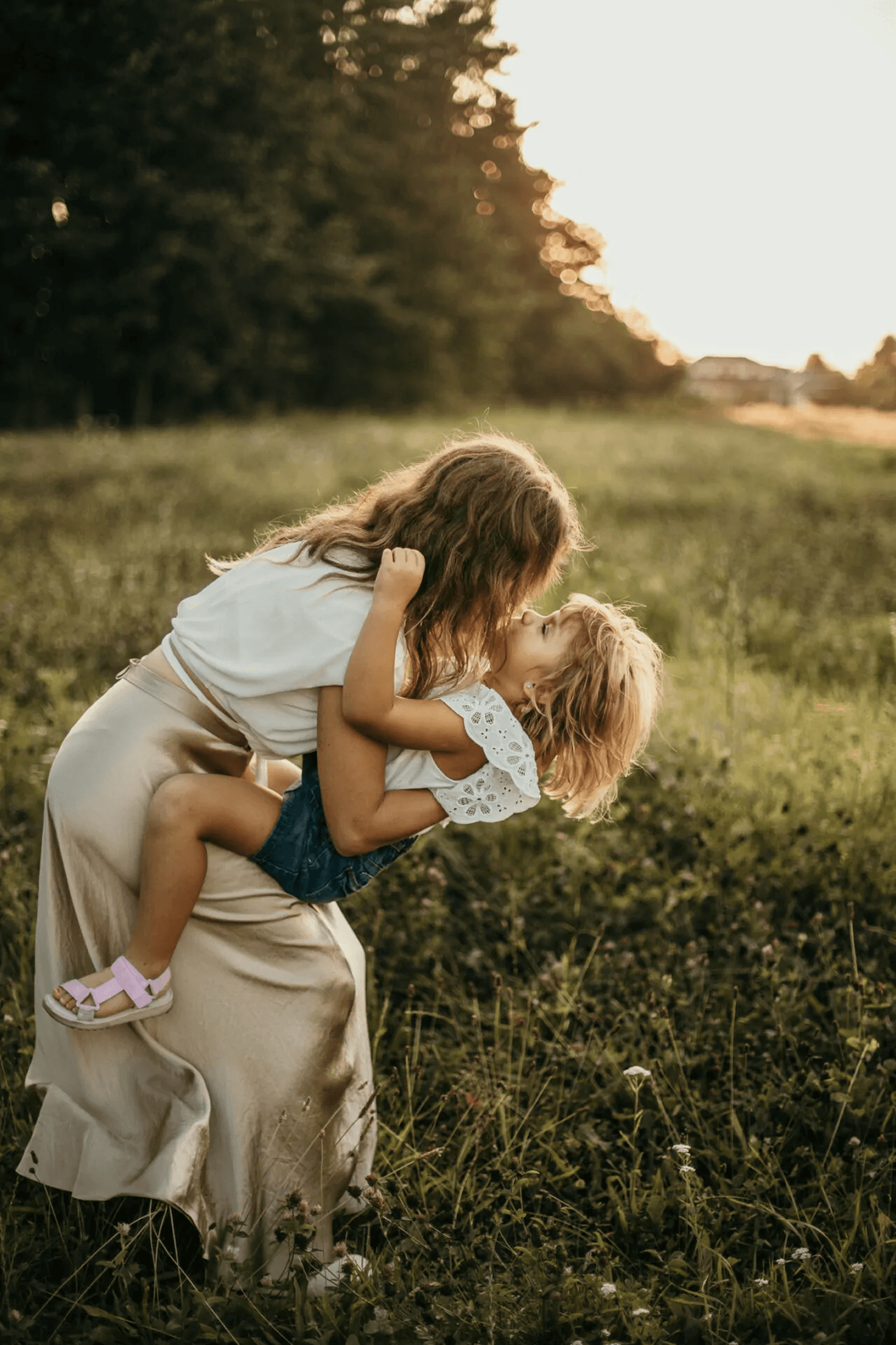Mother hugging her little daughter in a golden meadow