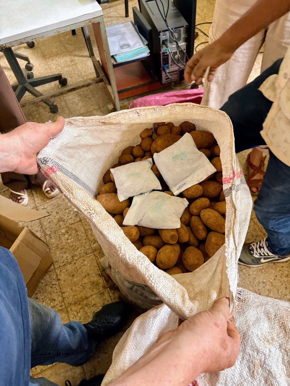 Smiling young man with short hair poses against a dark background, wearing a green button-up shirt.