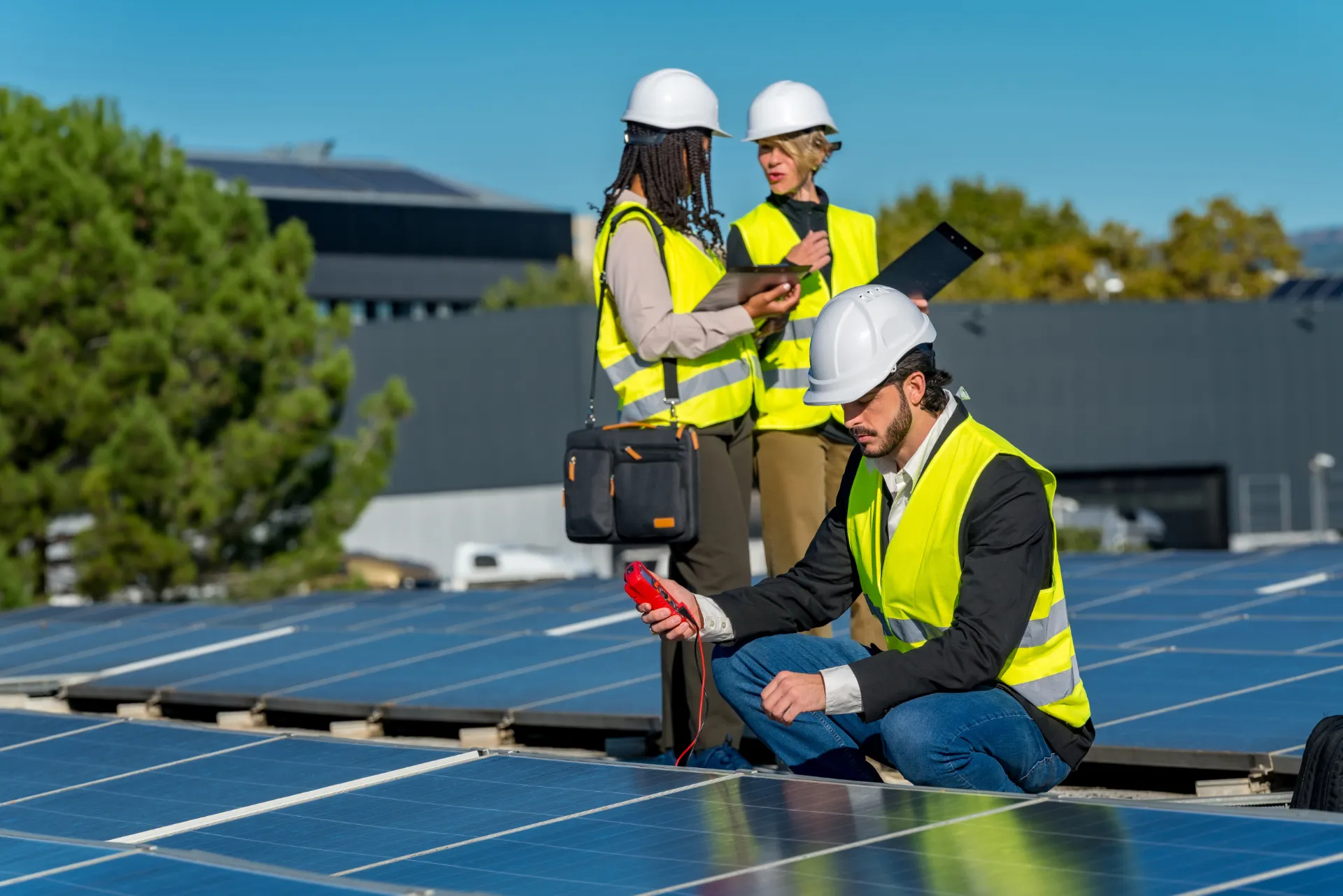 Ein Team an Bauherren, welche gerade um die fertig montierte Photovoltaikanlage auf einem Dach stehen