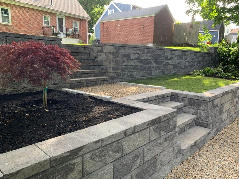 Price Landscape and Construction finished project at a residential home with stone retaining wall, grass, and gardens