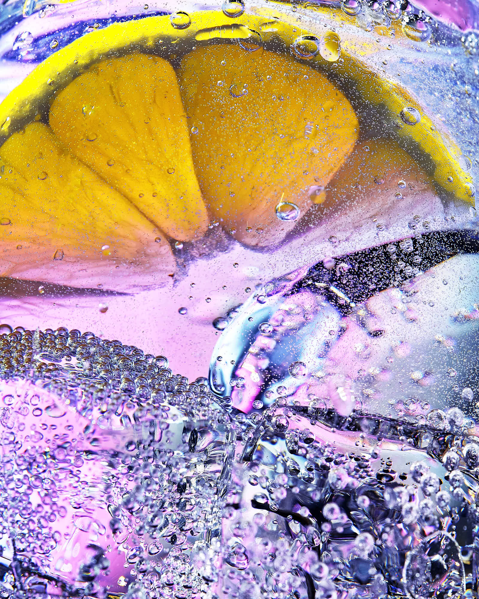Close-up of a bright yellow slice of lemon on a colorful, textured background with shades of pink and blue.