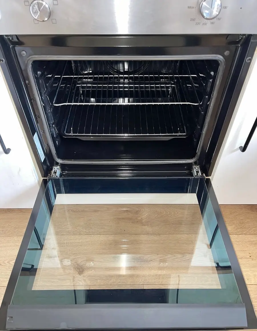 A deep-cleaned oven interior with a crystal-clear glass door and degreased racks, showcasing professional appliance cleaning as part of a move-in service.