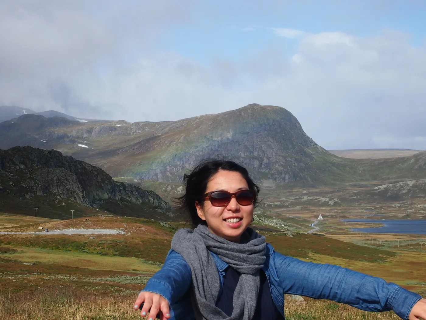 Hye Yoon wearing sunglasses and smiling, with mountains in the background