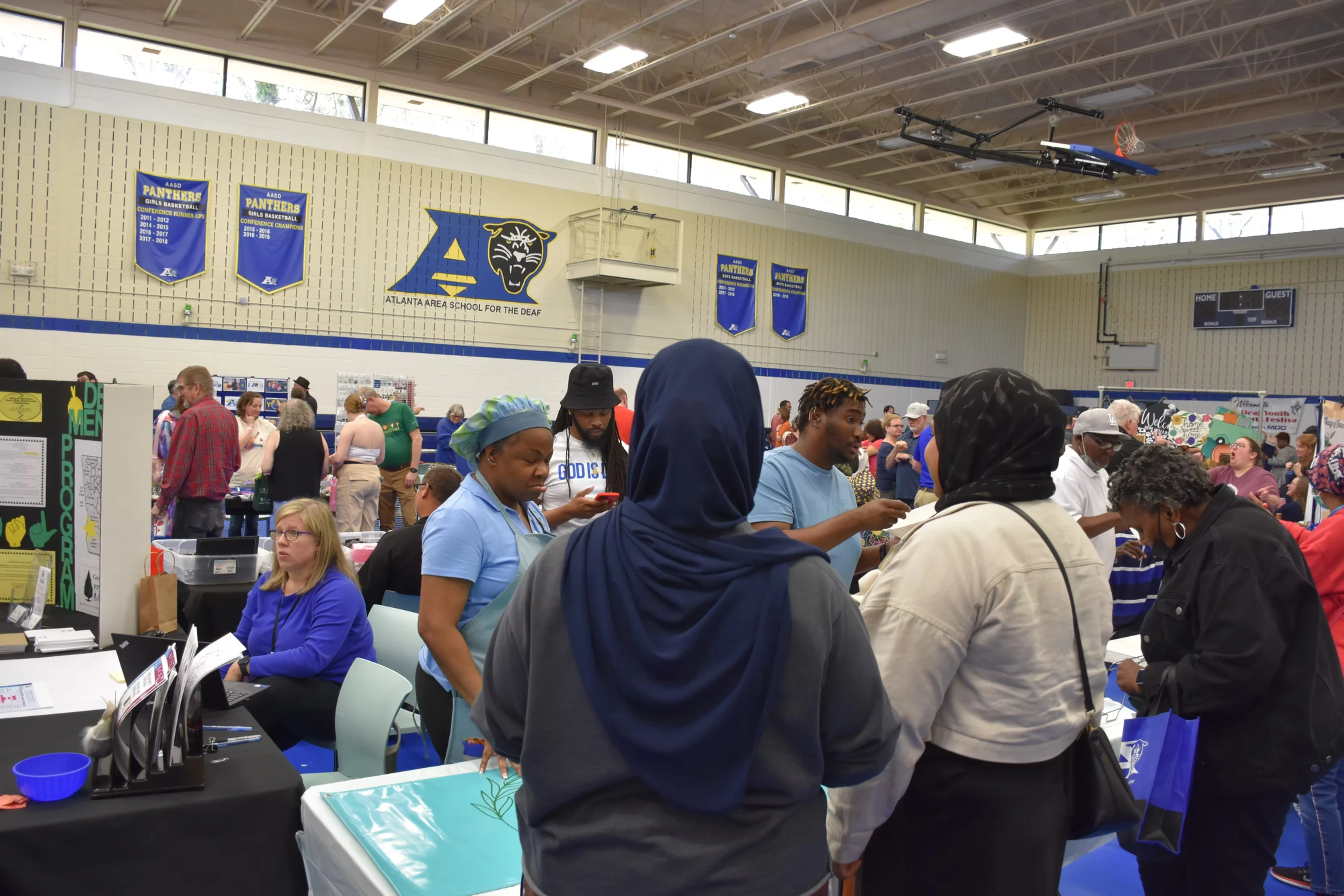 A large group of people at a school event, looking at displays and talking to each other.