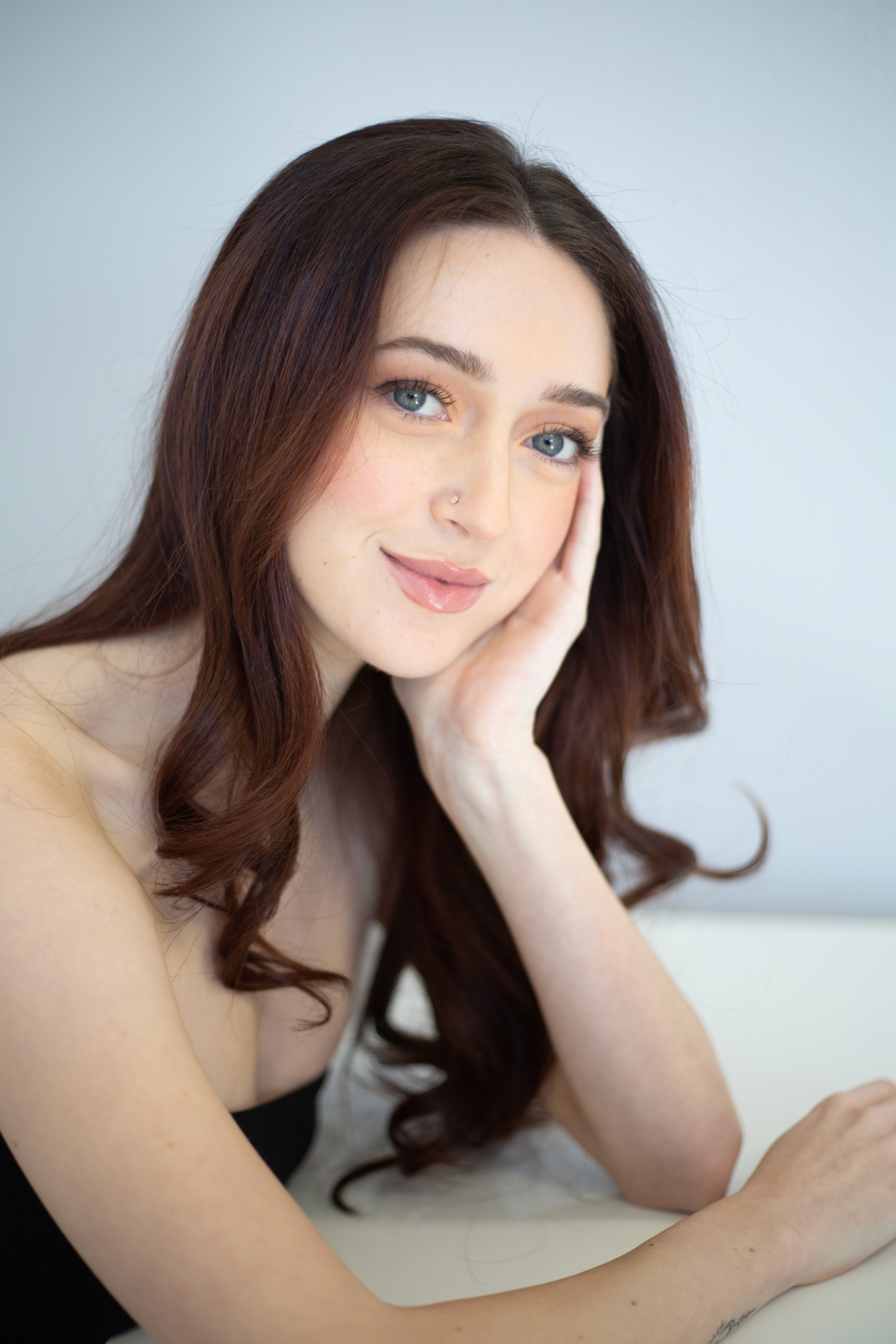Portrait of a person with natural makeup against a neutral background.