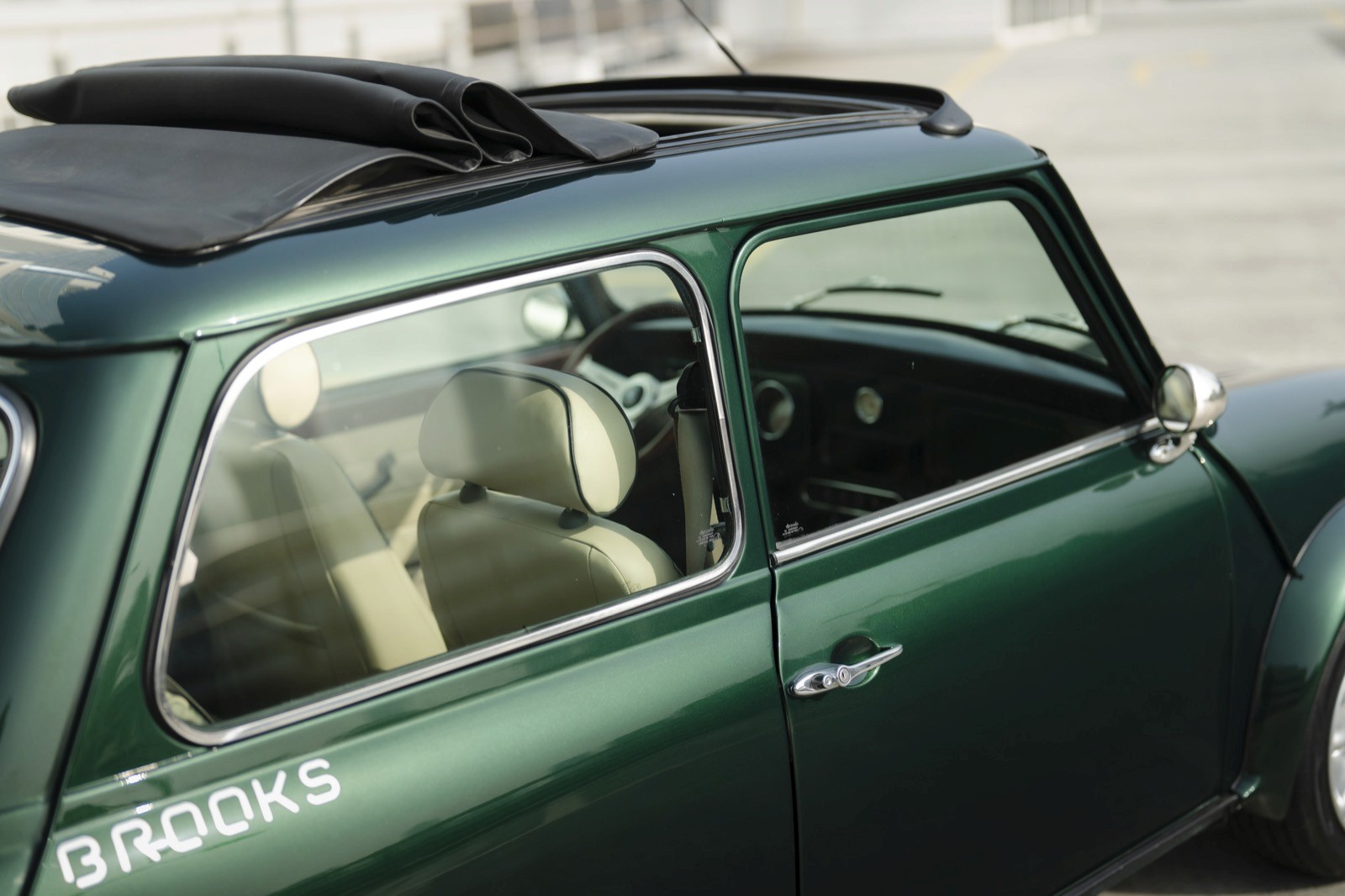 A green car with an open window, revealing its interior and a passenger seat.