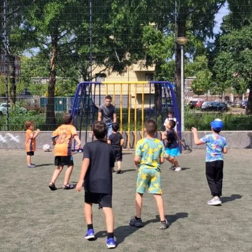 Kinderen voetballen op een veldje in de buurt